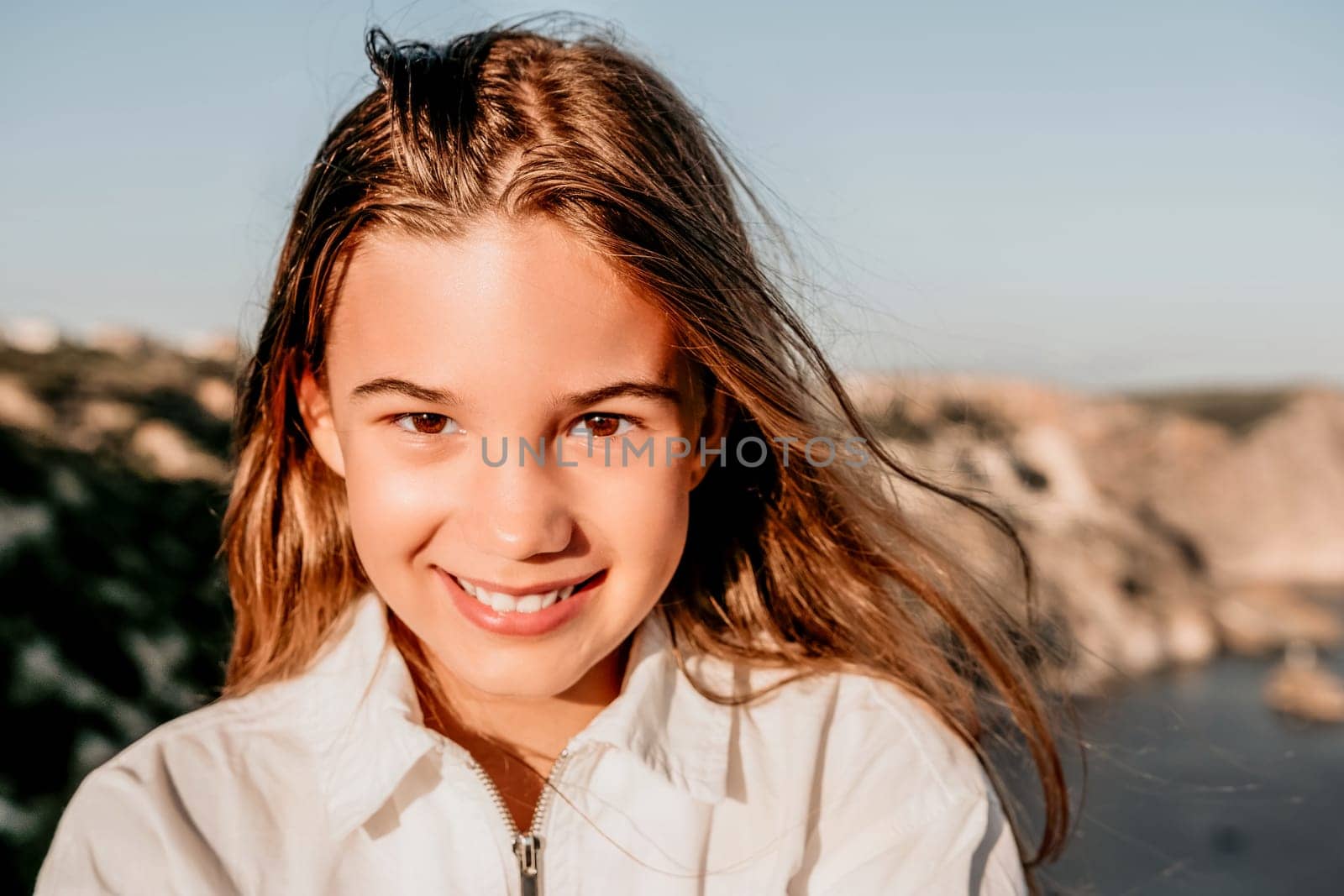 Adorable teenage girl outdoors enjoying sunset at beach on summer day. Close up portrait of smiling young romantic teenager girl with long hair on beach at summer evening. Travel and holidays by panophotograph