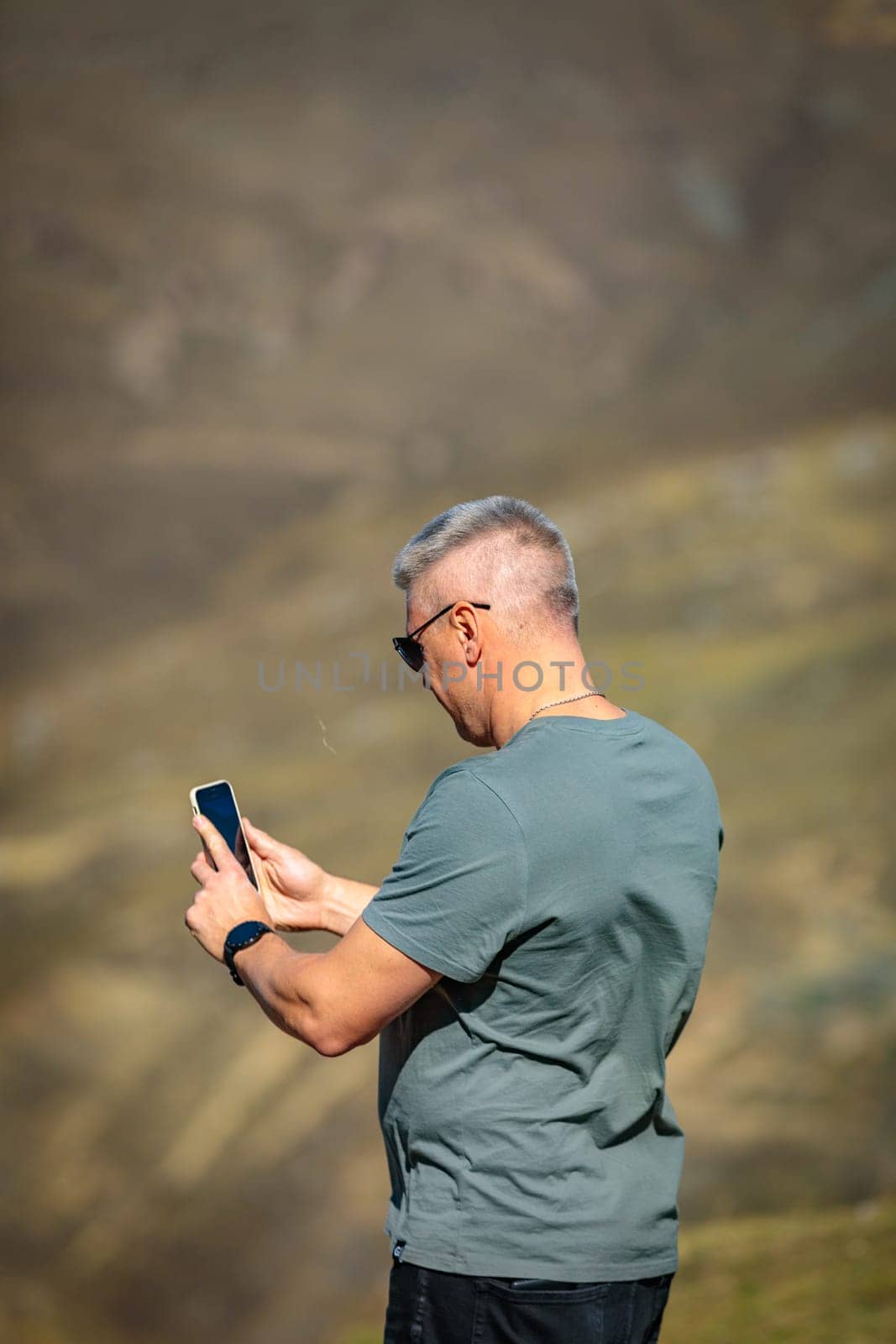 Man taking pictures of the beauty of the mountainous area using his mobile phone