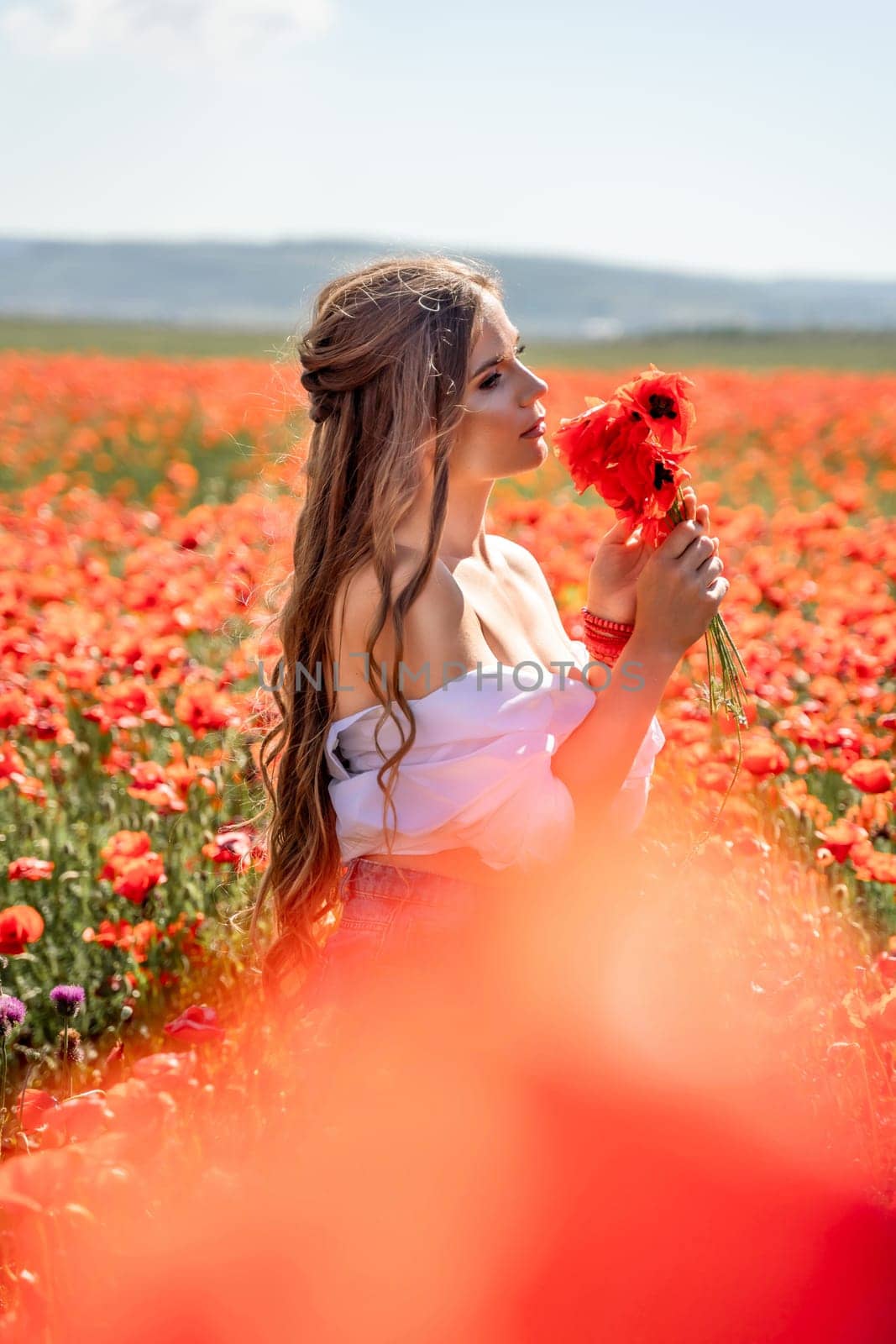 Woman poppies field. Side view of a happy woman with long hair in a poppy field and enjoying the beauty of nature in a warm summer day