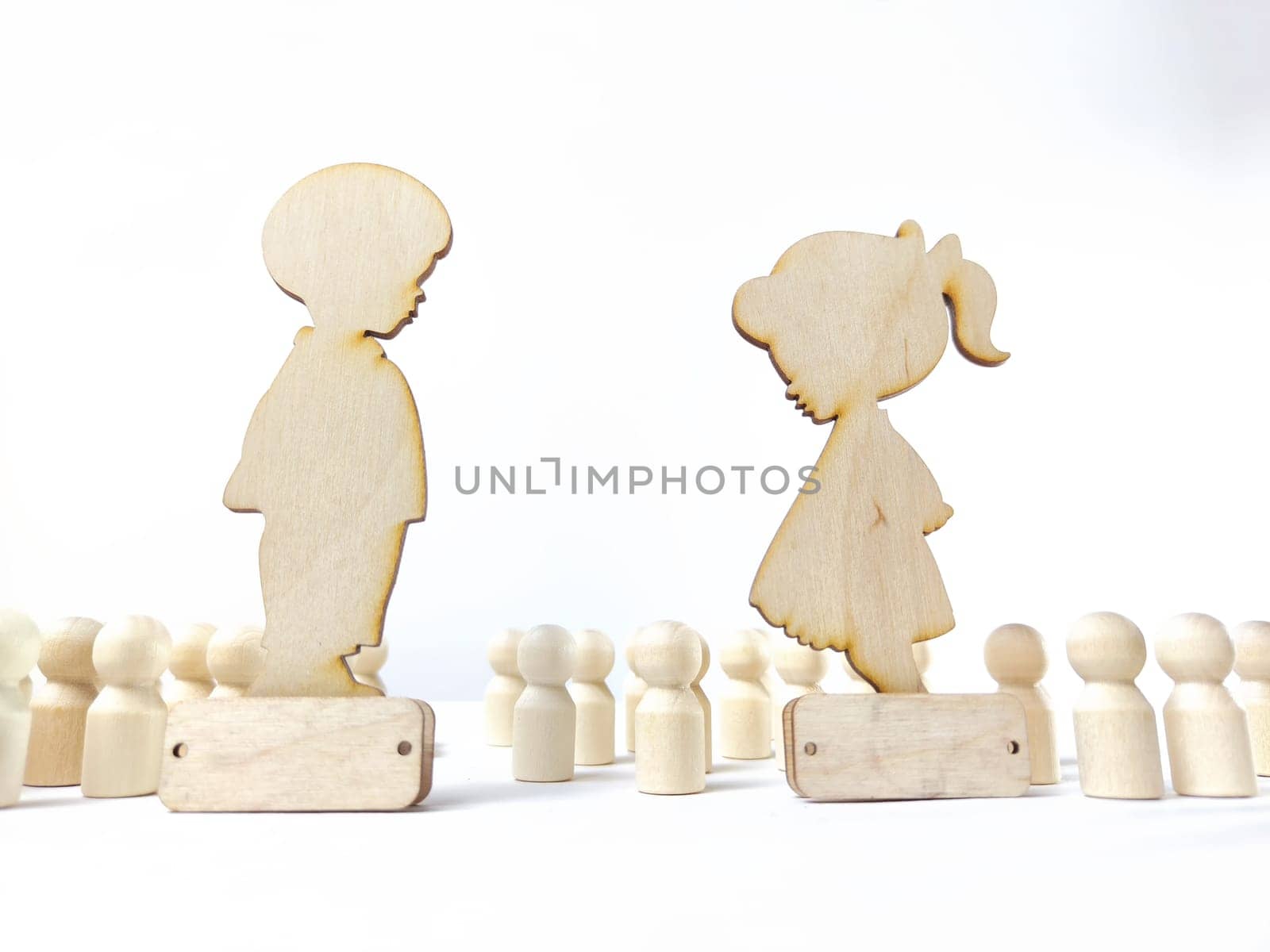 Wooden figures of a girl and a boy against a background of faceless people. A couple in love does not notice anyone around. Love is the most important thing