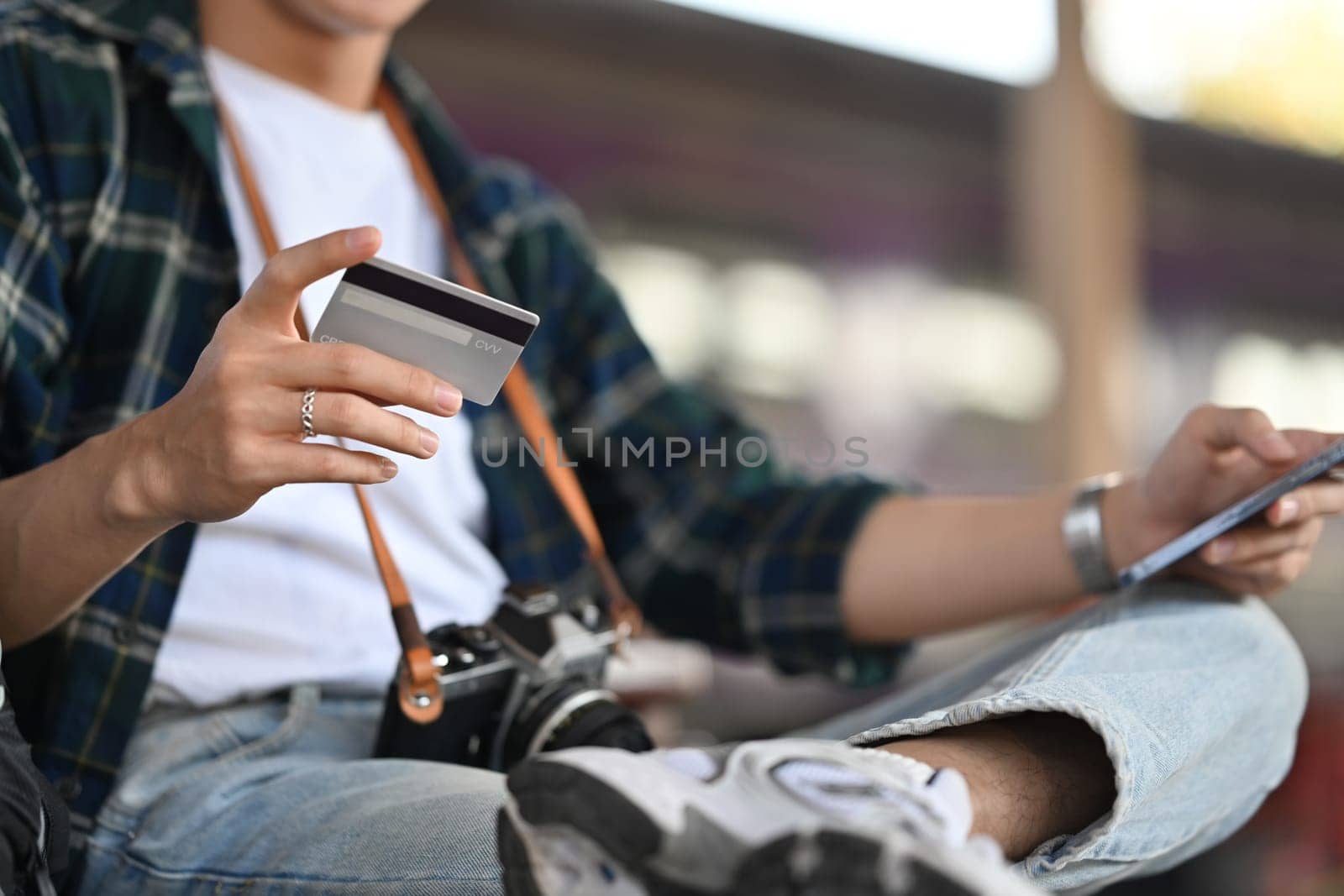 Tourist man holding credit card making hotel reservation online on mobile phone.