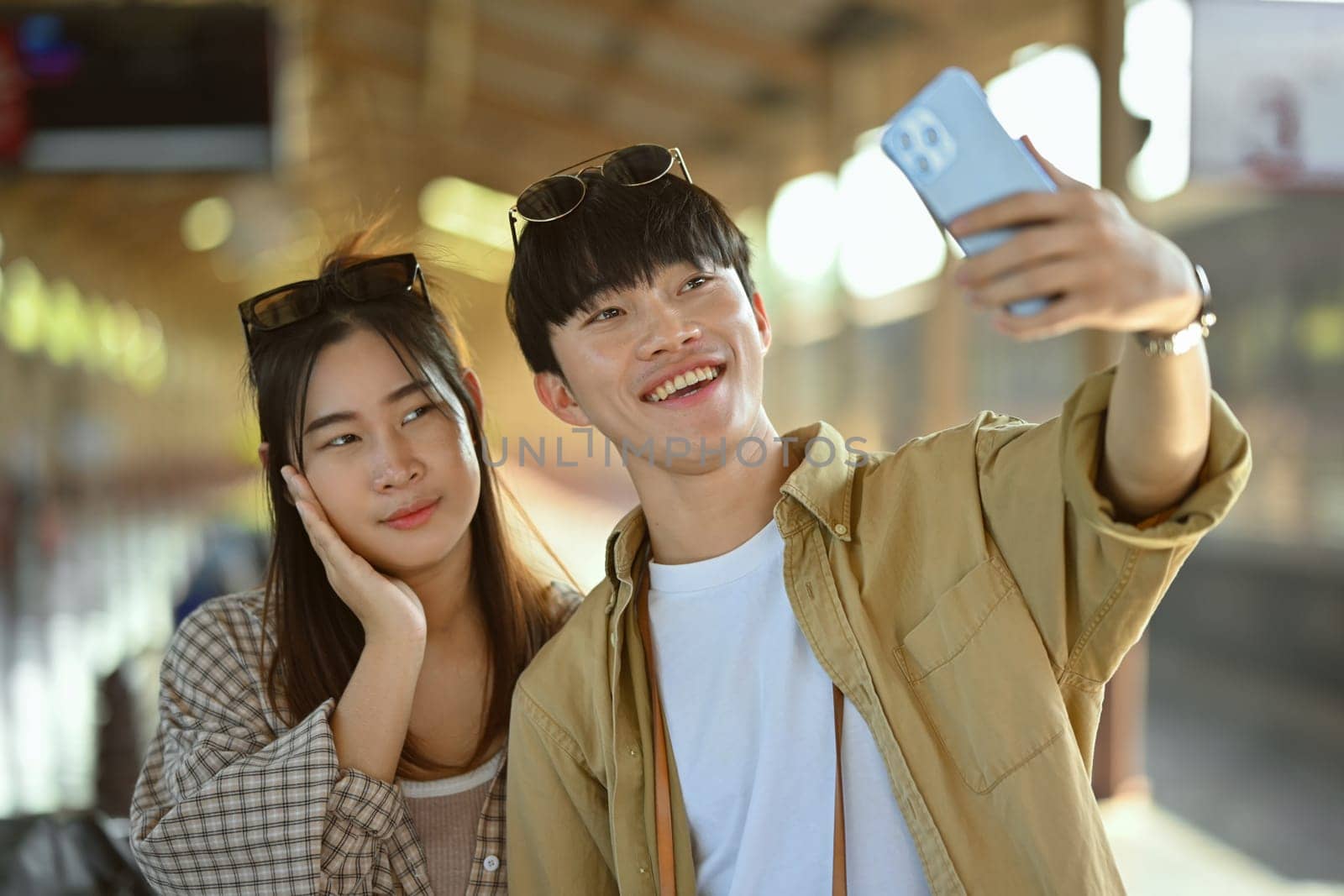 Happy and excited young couple tourists taking a selfie at train station. Travel and lifestyle concept.