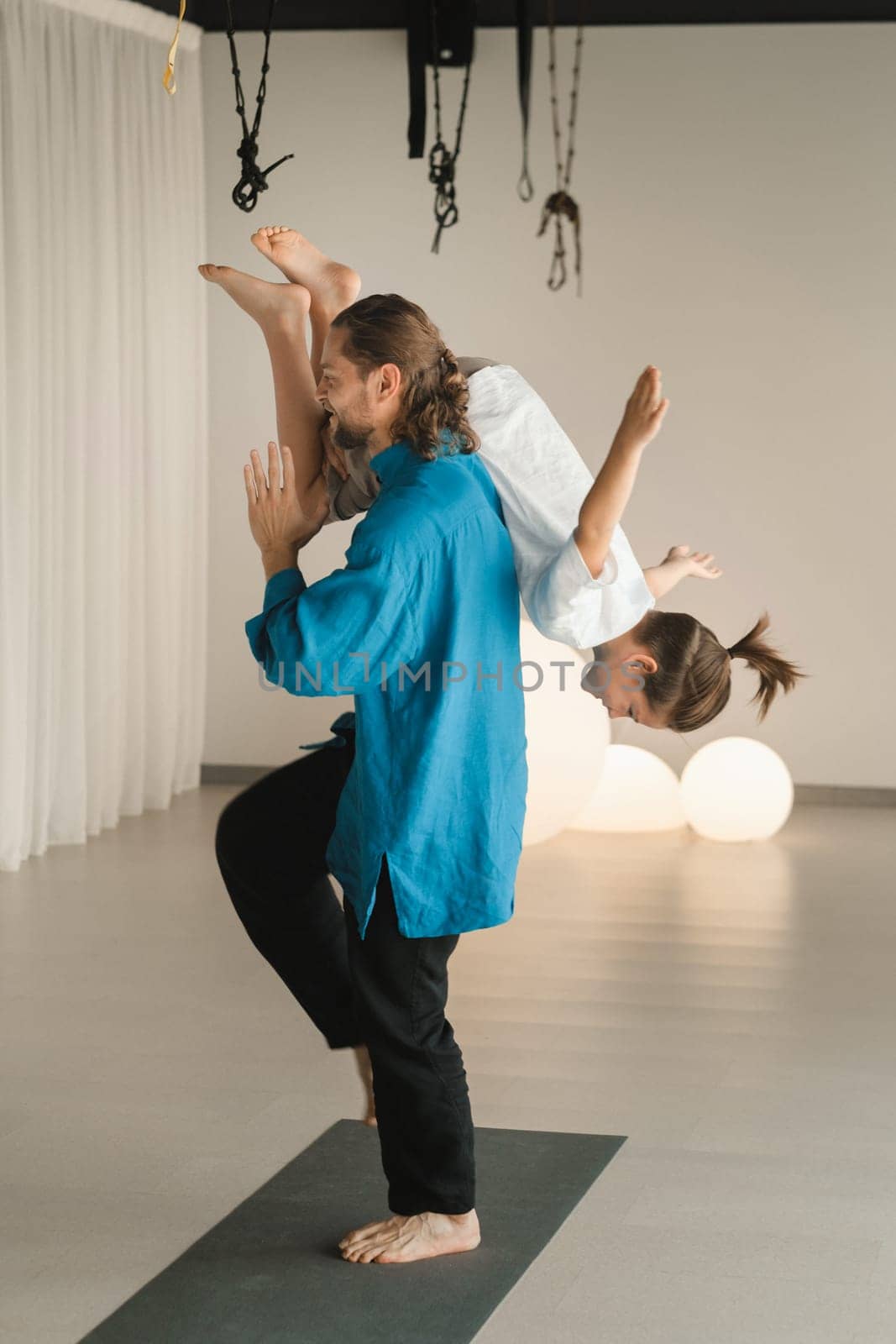 Yoga instructor in training messing with a child holding on his shoulders in the gym by Lobachad