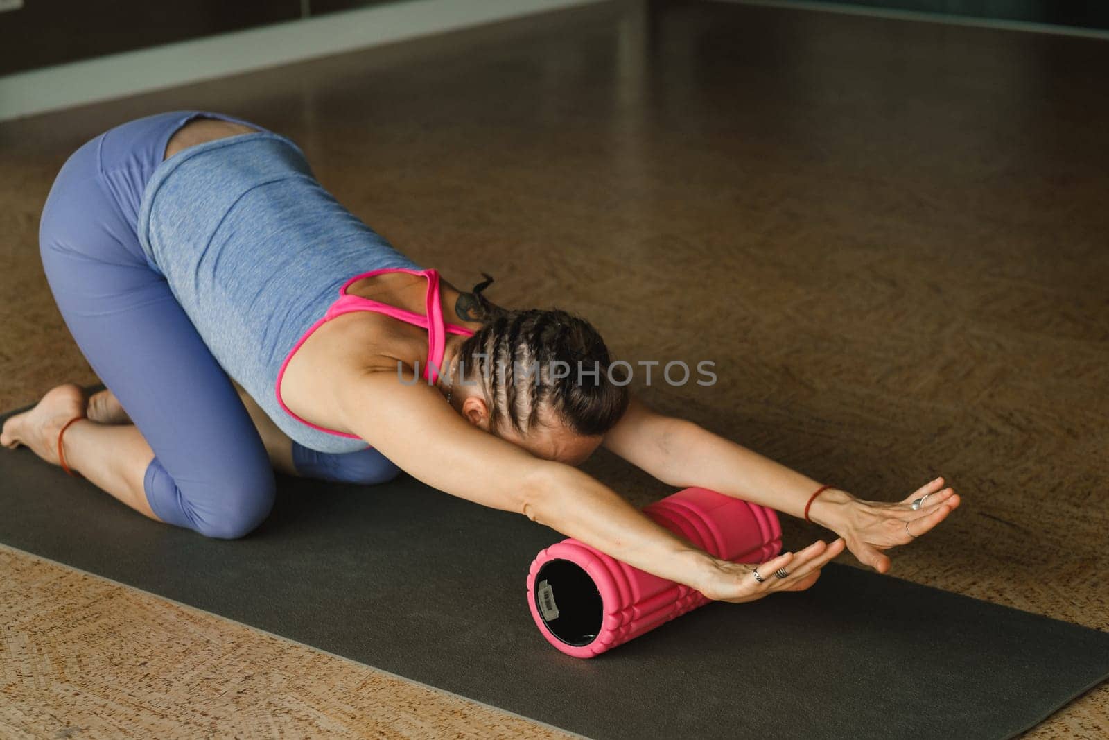 Slender girl doing yoga with a big massage roller on the floor by Lobachad