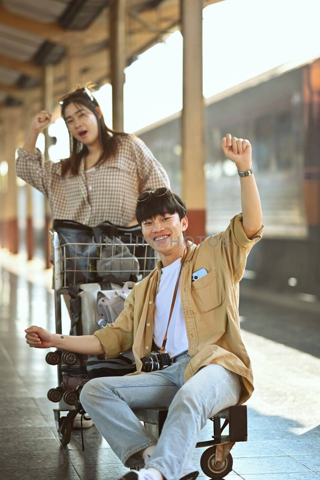 Cheerful young Asian couple arriving at train station while traveling on their vacation. Travel and lifestyle concept. by prathanchorruangsak