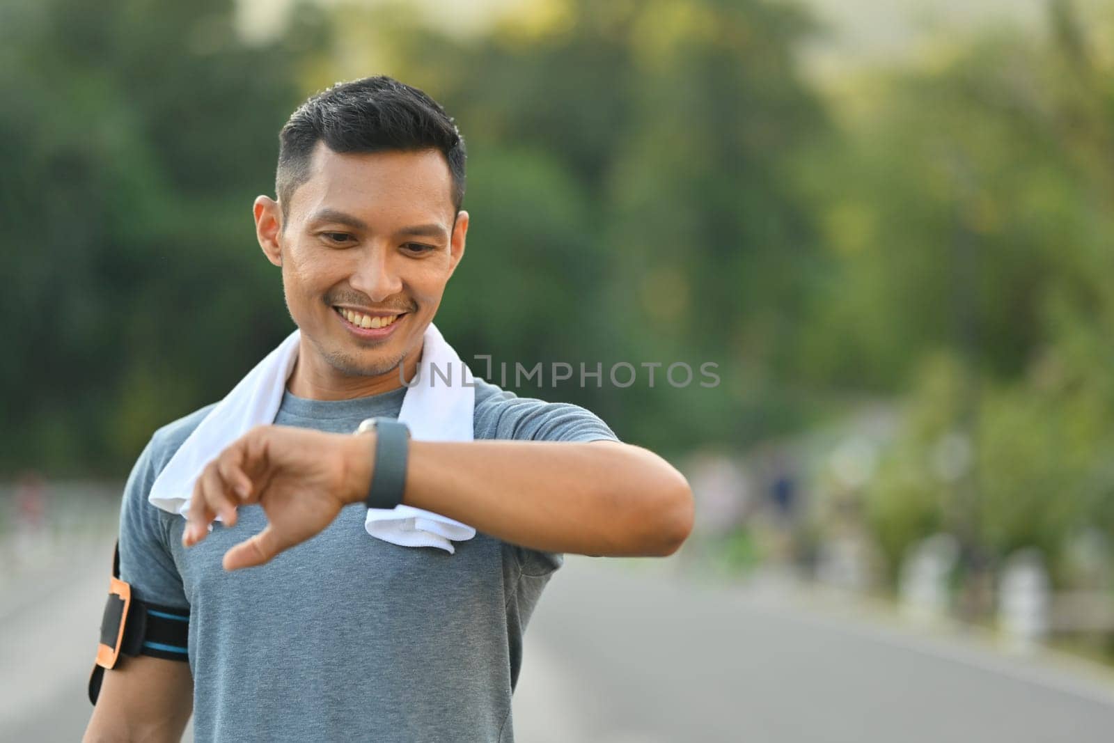 Young athlete checking fitness progress on his smart watch after training outdoors.