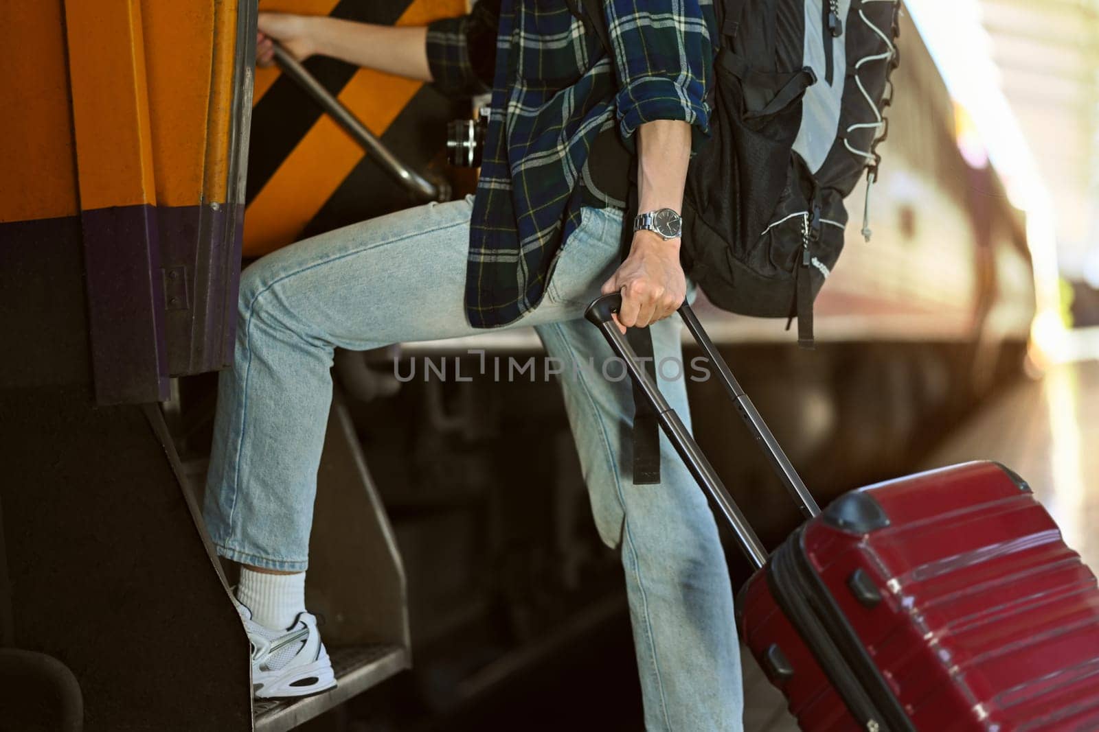 Cropped shot male traveler with suitcase getting on the train. Travel and vacations concept.