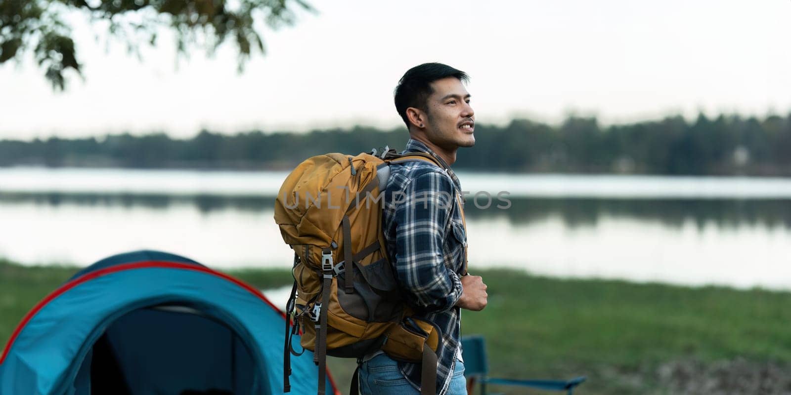 Young man backpacker traveling alone. Attractive male traveler walking in nature wood lake during holiday vacation trip by itchaznong