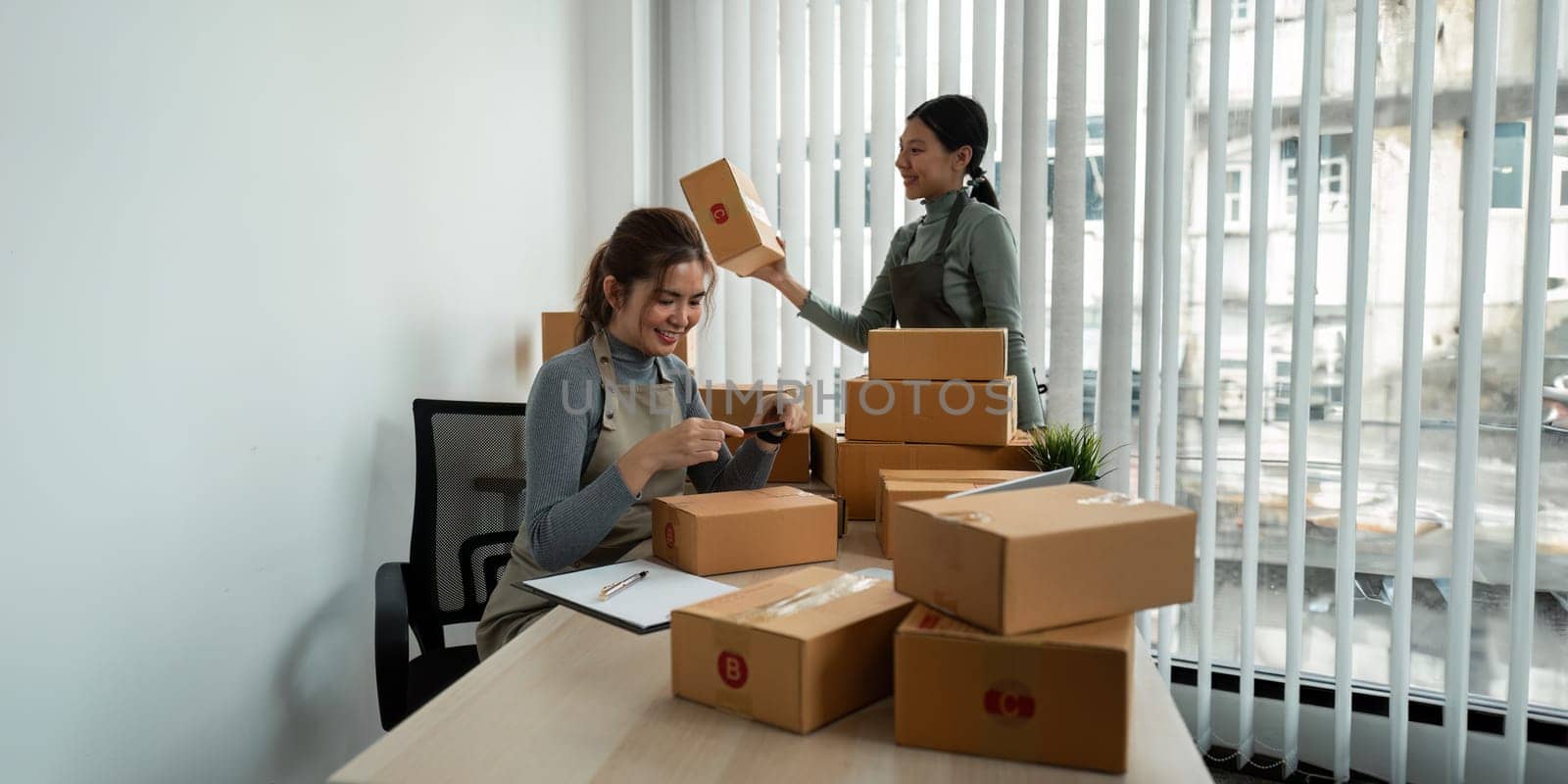 Young business woman entrepreneur online shipment business is preparing packages to send to customer. e-commerce concept by itchaznong