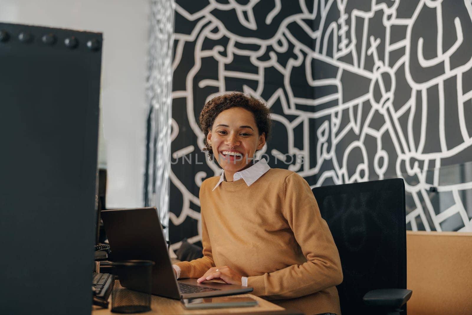 Pretty female freelancer working on laptop while sitting on modern coworking background