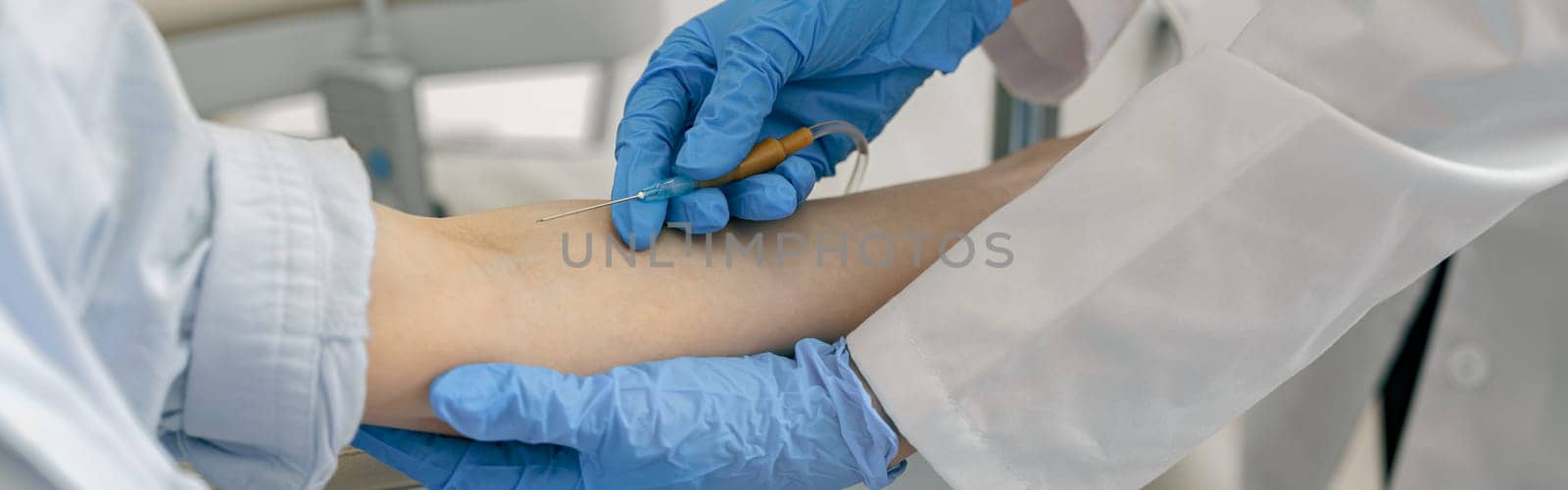 Close-up of doctor putting an IV drip to patient intravenously in hospital ward by Yaroslav_astakhov