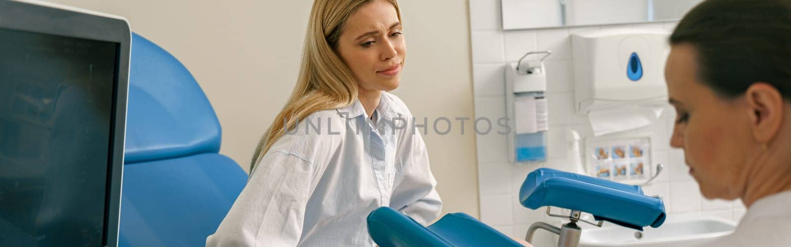 Young woman on appointment with her gynecologist during regular visit to women's consultation by Yaroslav_astakhov