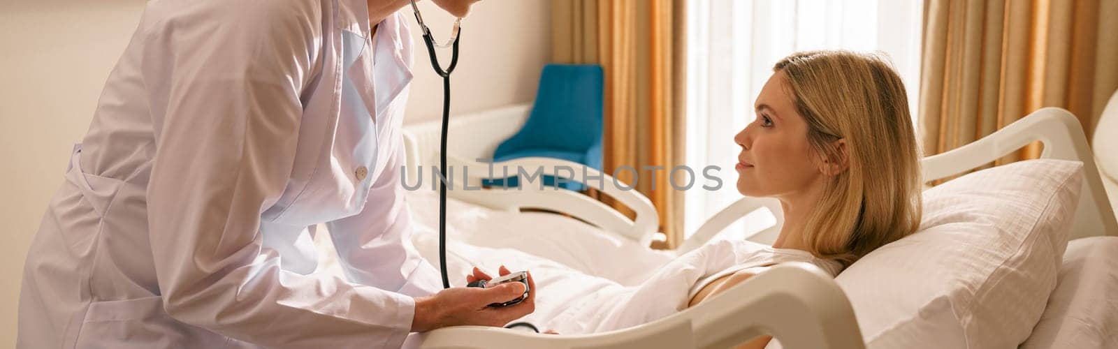 Doctor checking blood pressure of young woman patient in ward of modern clinic. High quality photo