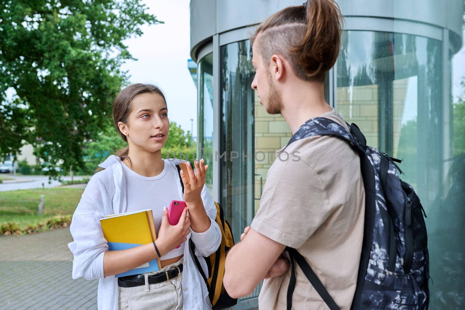 Meeting of two teenage students, guy and girl, near educational building by VH-studio