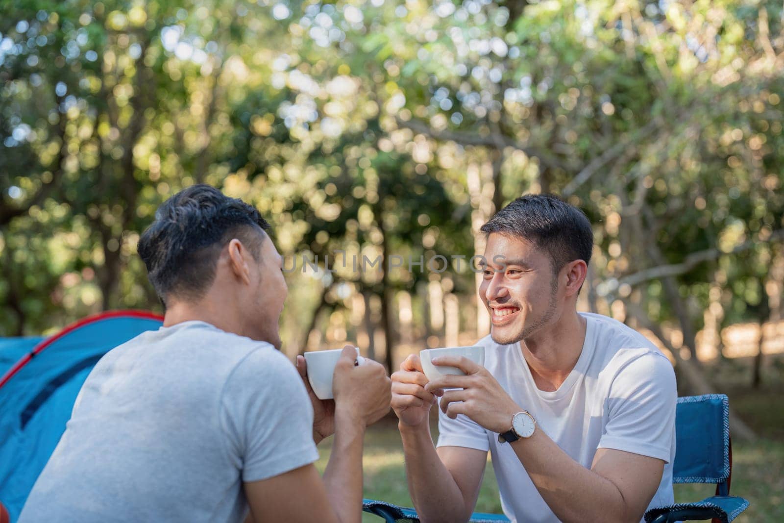 Male gay couple asian traveling with tent camping outdoor and various adventure lifestyle hiking active summer vacation. drinking coffee and talking together by nateemee