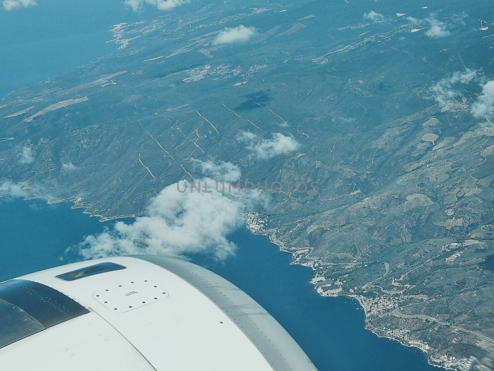 view from the airplane window and blue sky with white clouds, cities, sea and green coast. soft focus