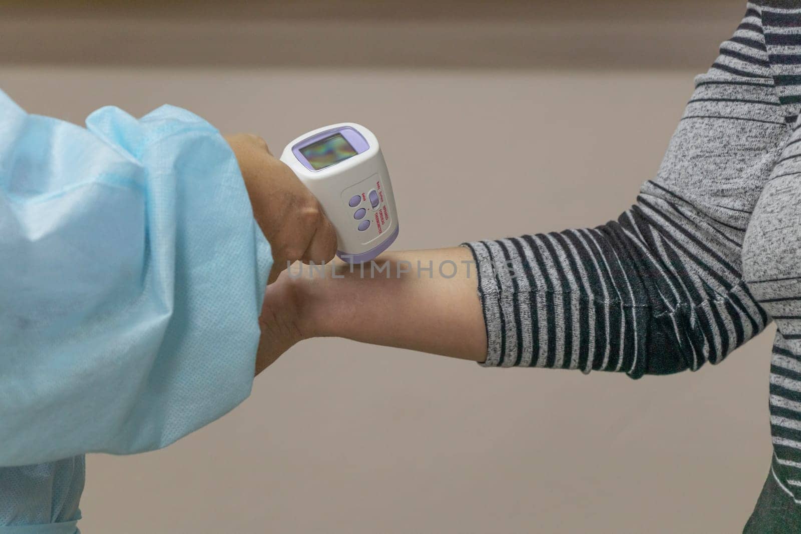 Close up hand of nurse in disposable medical suit measures body temperature using medical infrared thermometer. Thermometer gun Isometric medical digital non-contact infrared. soft focus by Leoschka