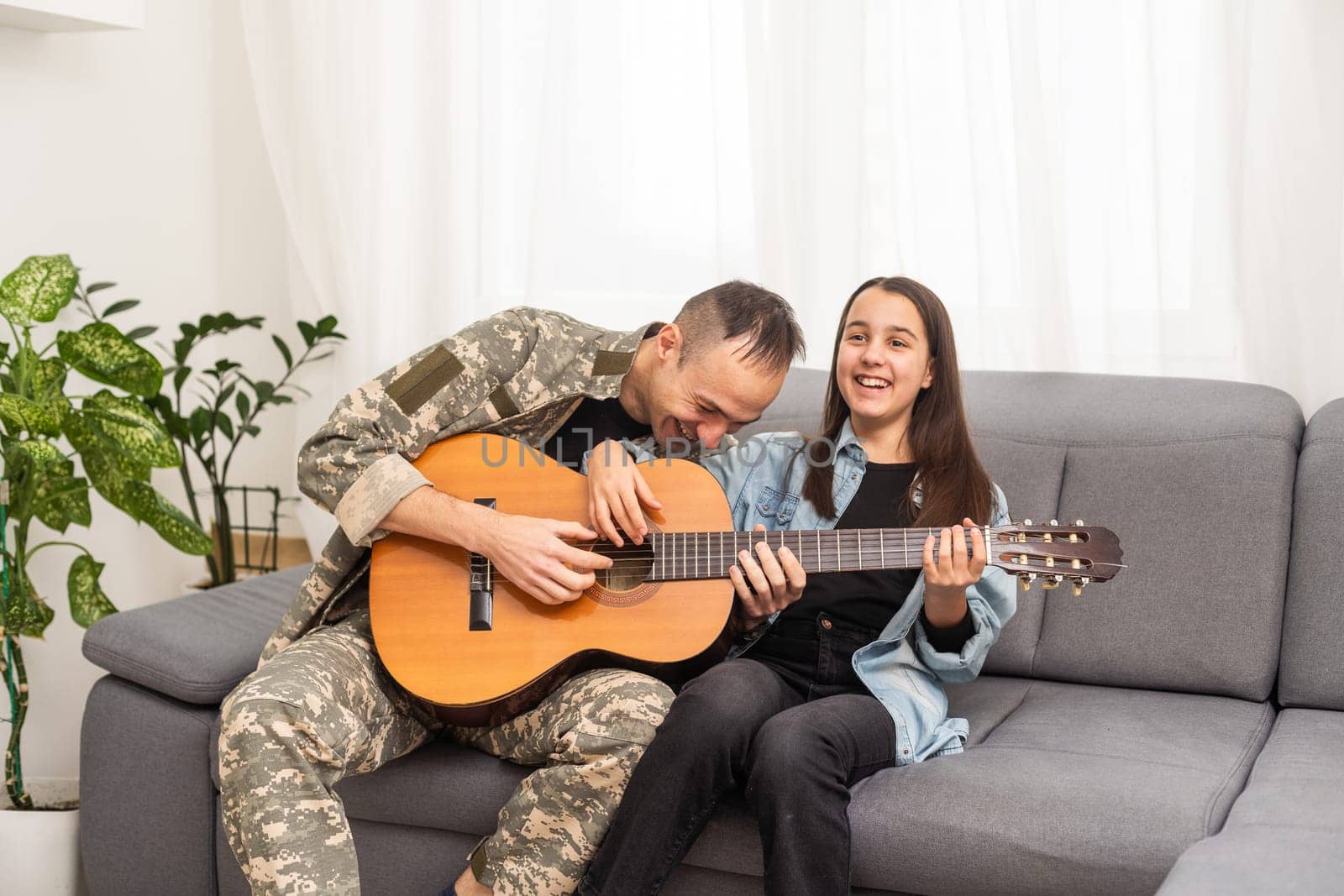 a veteran and his daughter play the guitar. High quality photo