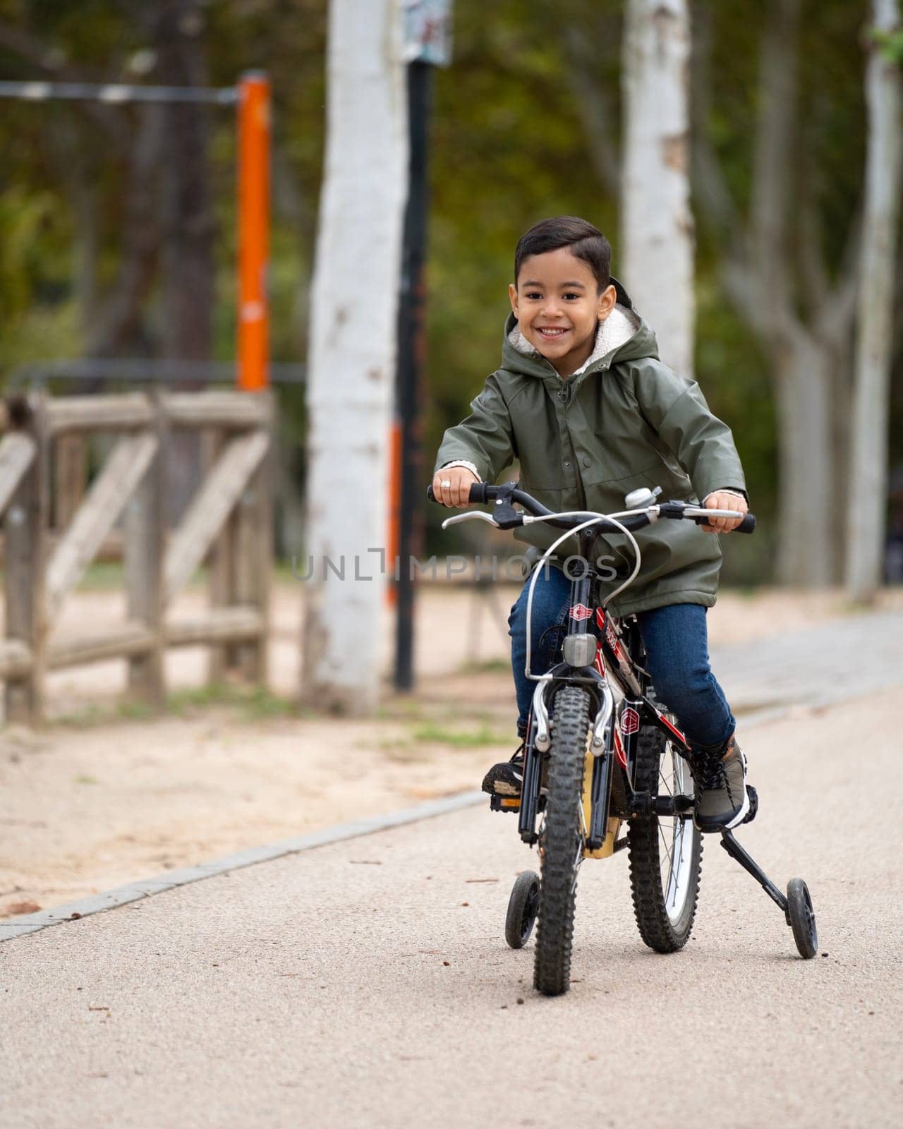 Portrait of happy boy riding a bicycle in a public park with copy space by papatonic