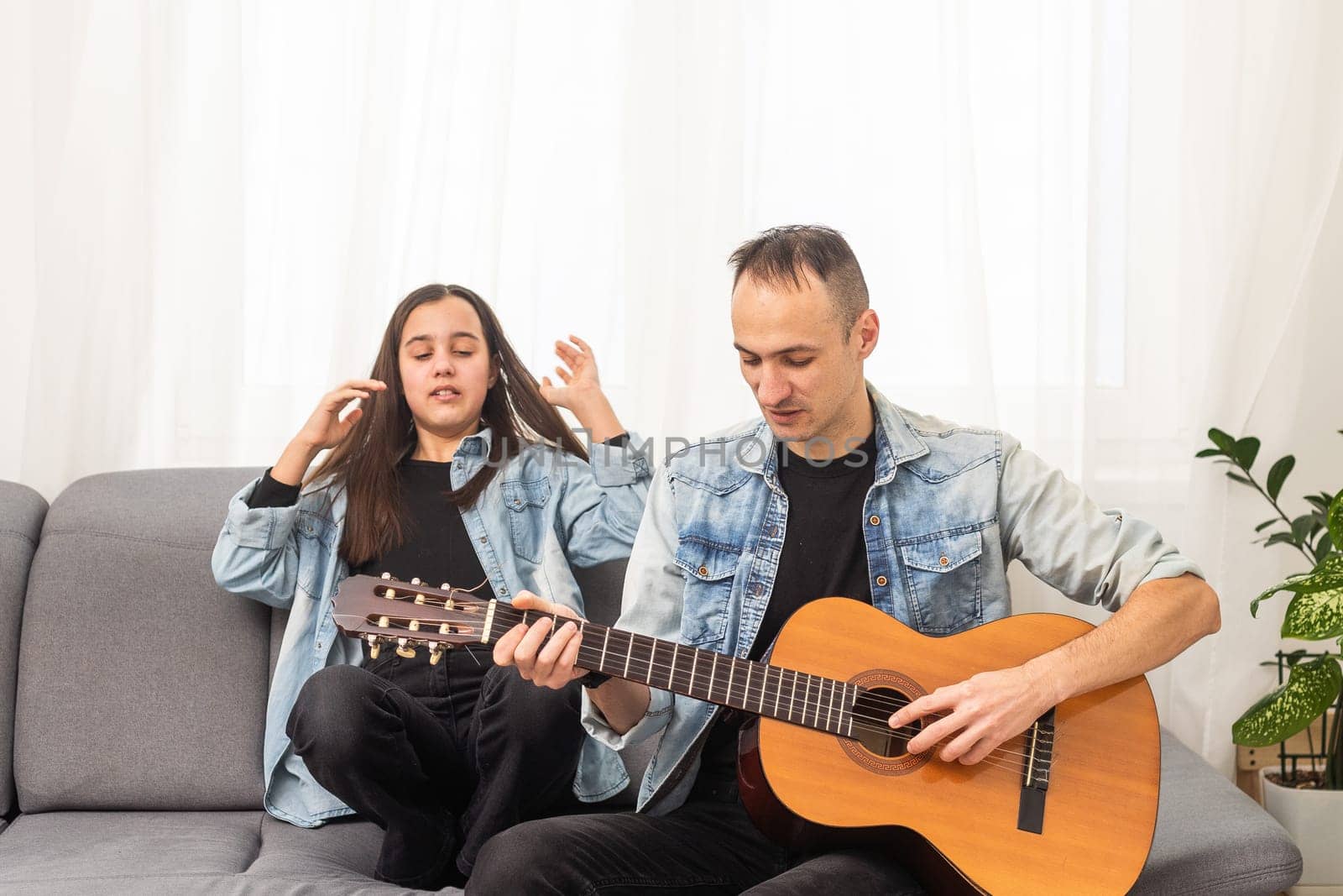 smiling father showing daughter how to play barre chord. High quality photo