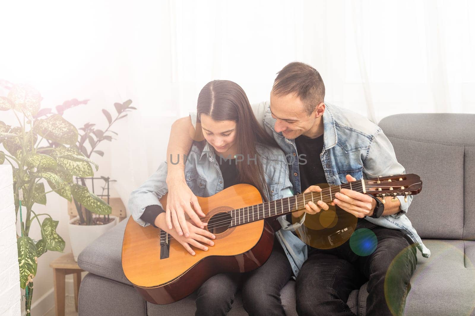 smiling father showing daughter how to play barre chord. High quality photo