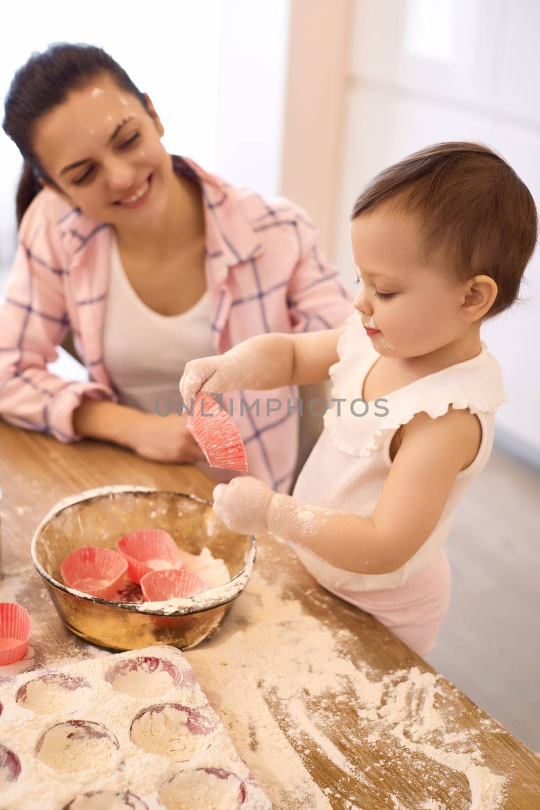 smiling mother and little baby girl baking in the kitchen, bake cookies. happy time together