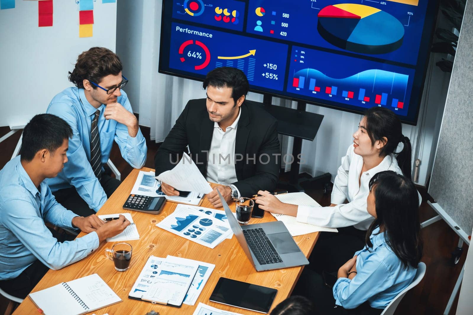 Wide top view of diverse group of business analyst team analyzing financial data report paper on meeting table. Chart and graph dashboard by business intelligence analysis. Meticulous