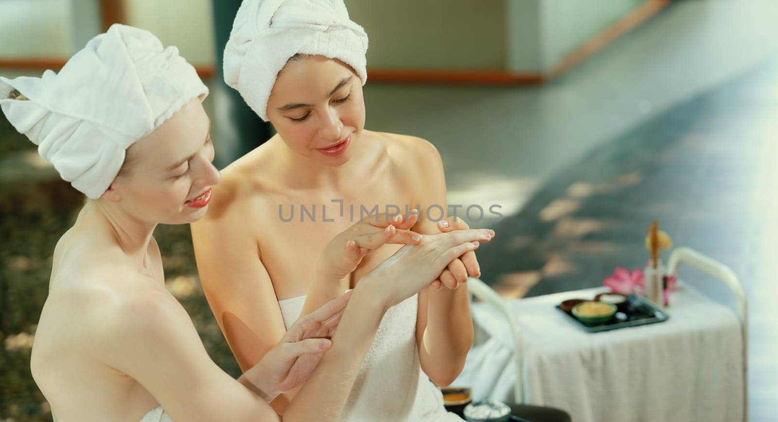 A portrait of two beautiful caucasian woman in white towel using homemade facial mask rounded by peaceful natural environment at outdoor. Healthy and beauty concept. Blurring background. Tranquility.