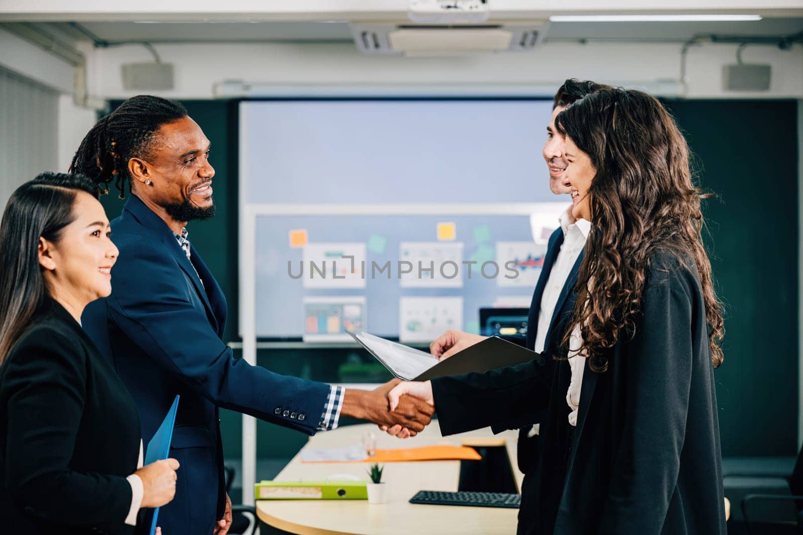 In a meeting, professionals seal a deal with a handshake, demonstrating their successful collaboration and agreement. Executives, lawyers, and managers celebrate their achievement. Teamwork by Sorapop