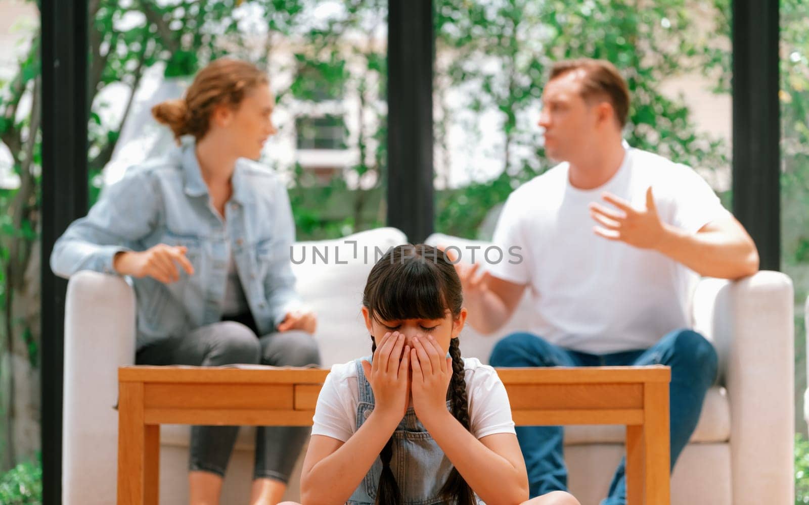 Stressed and unhappy young girl crying and trapped in middle of tension by her parent argument in living room. Unhealthy domestic lifestyle and traumatic childhood develop to depression. Synchronos