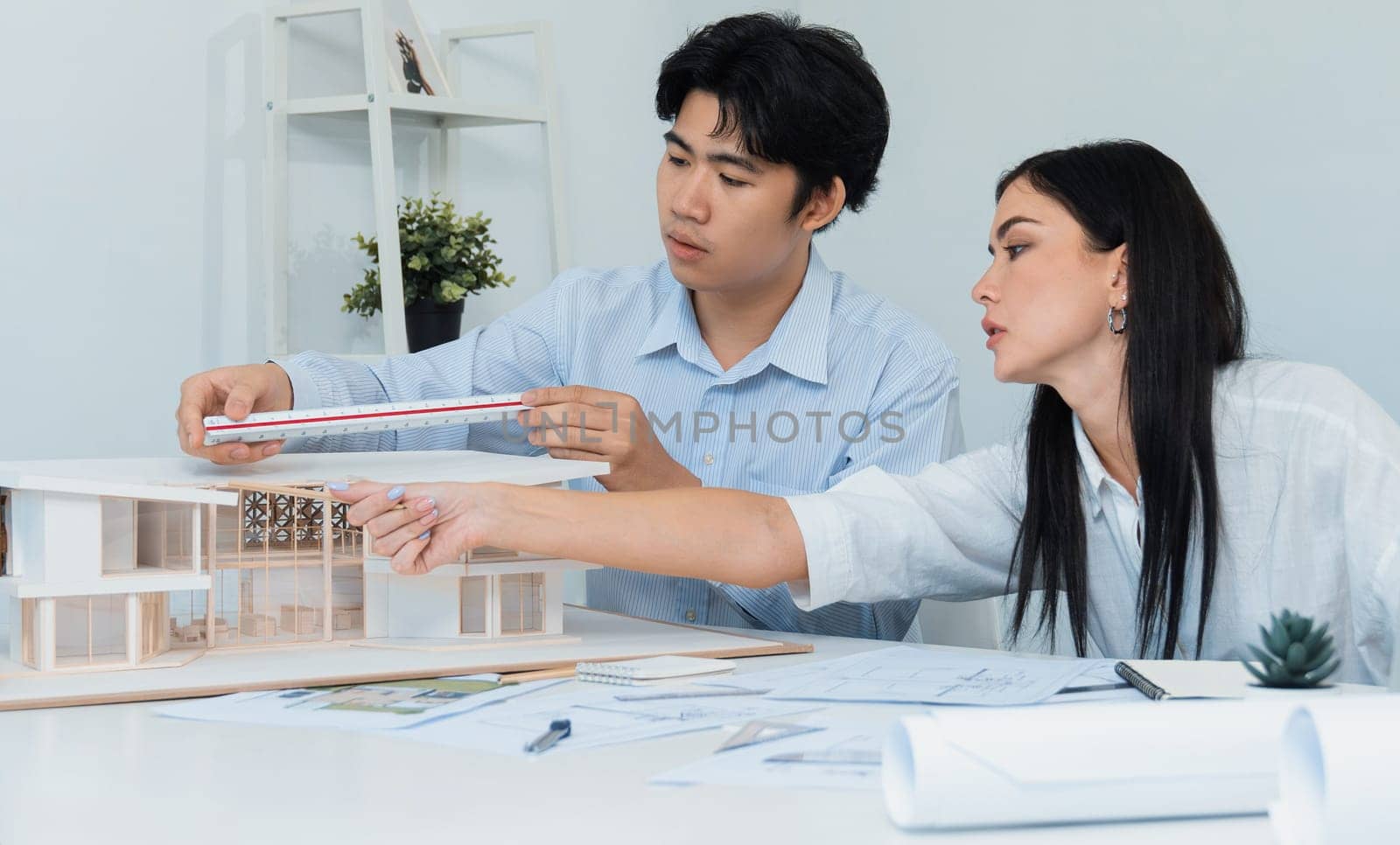 Portrait of cooperative engineer team working together to measure house model by using ruler and architectural equipment. Creative business design and teamwork concept. Immaculate..