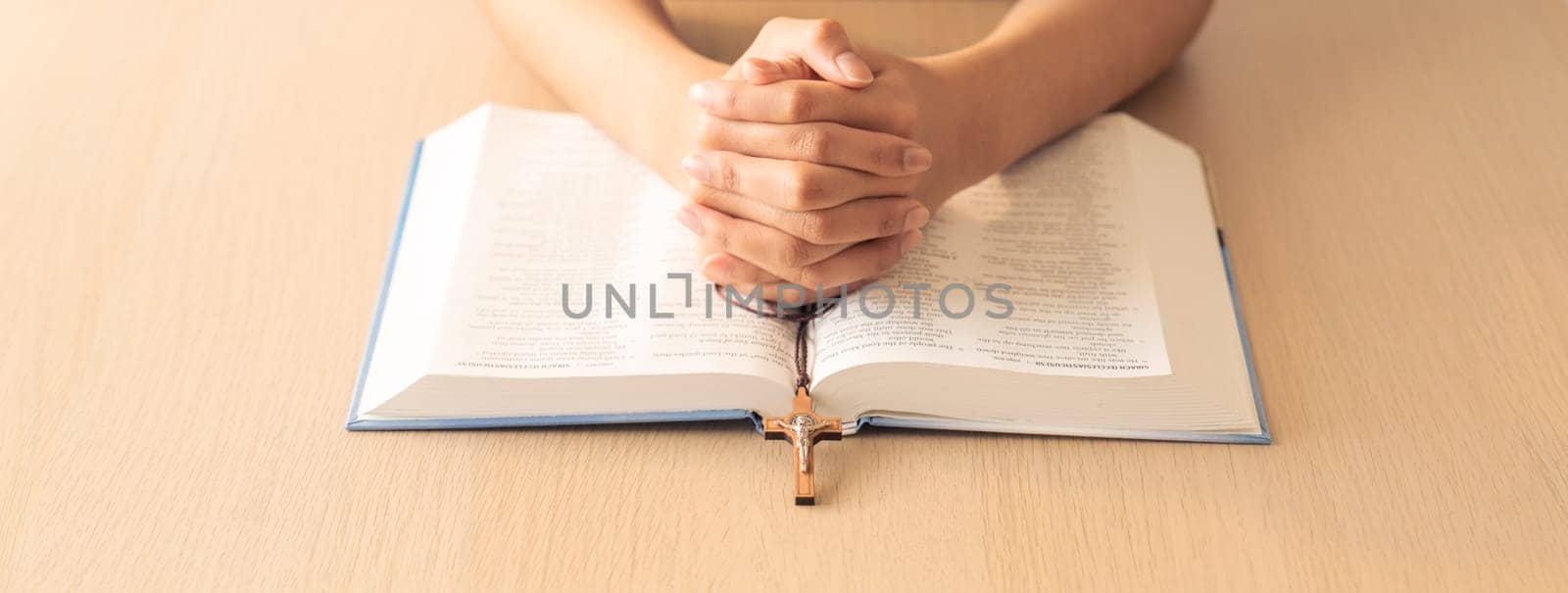 Praying male hand holding cross on holy bible book at wooden table. Burgeoning. by biancoblue