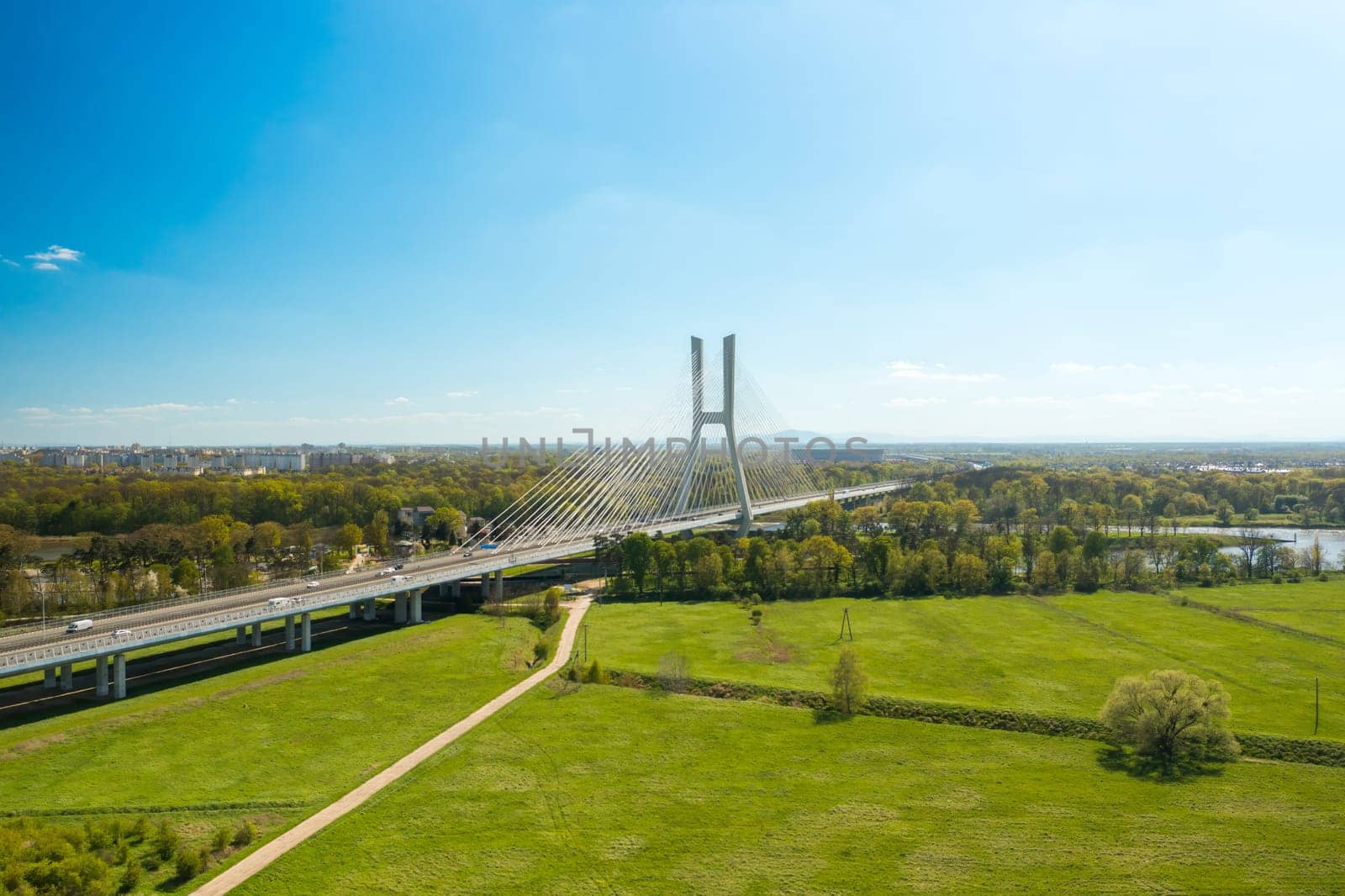 Pylon bridge with cars over green island on Oder river in Wroclaw. Cable-stayed Redzinski Bridge and scenic spring landscape aerial view