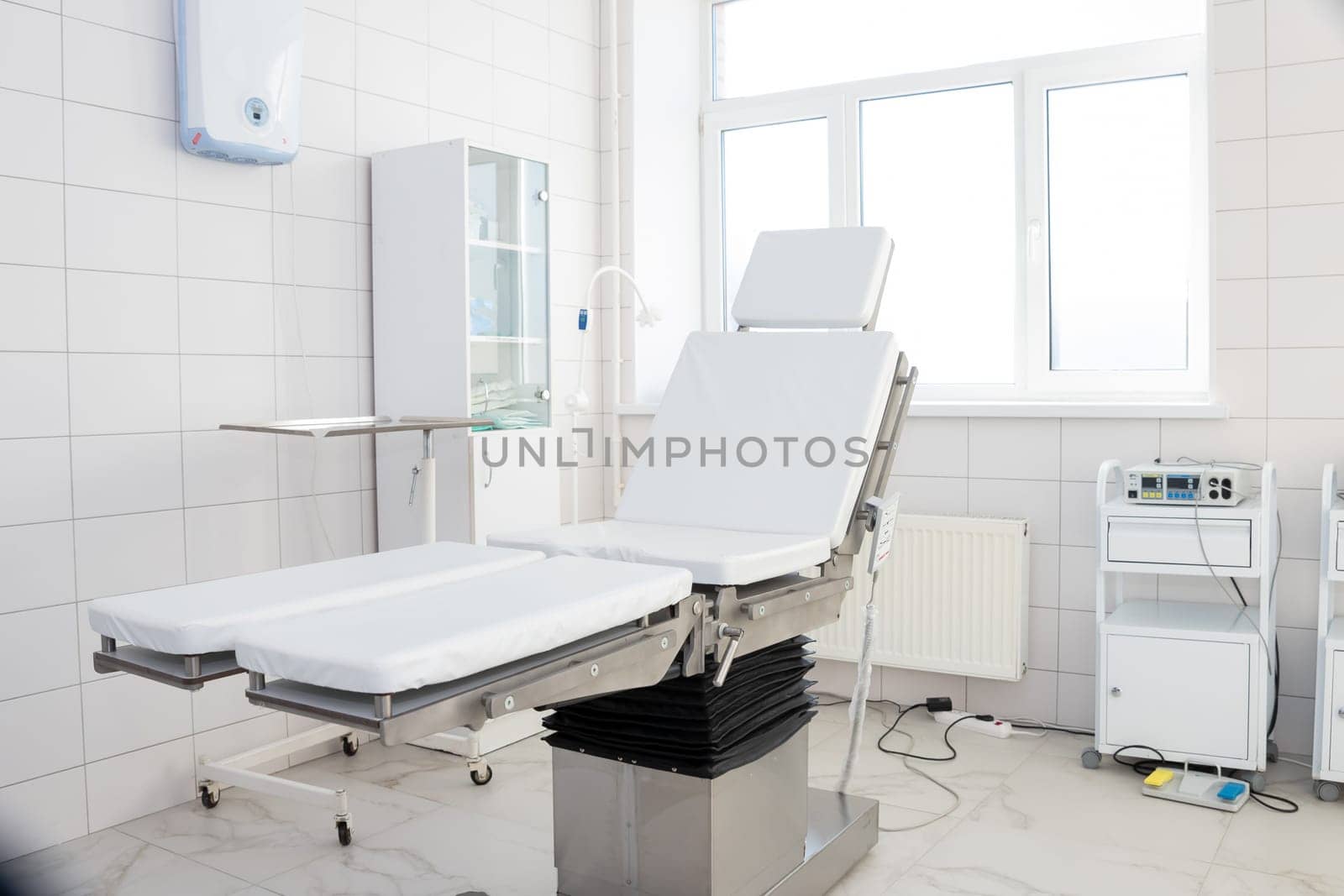 Hospital interior design with operating table and lamp with cabinets and modern devices in light surgery room.modern equipment in the hospital by YuliaYaspe1979