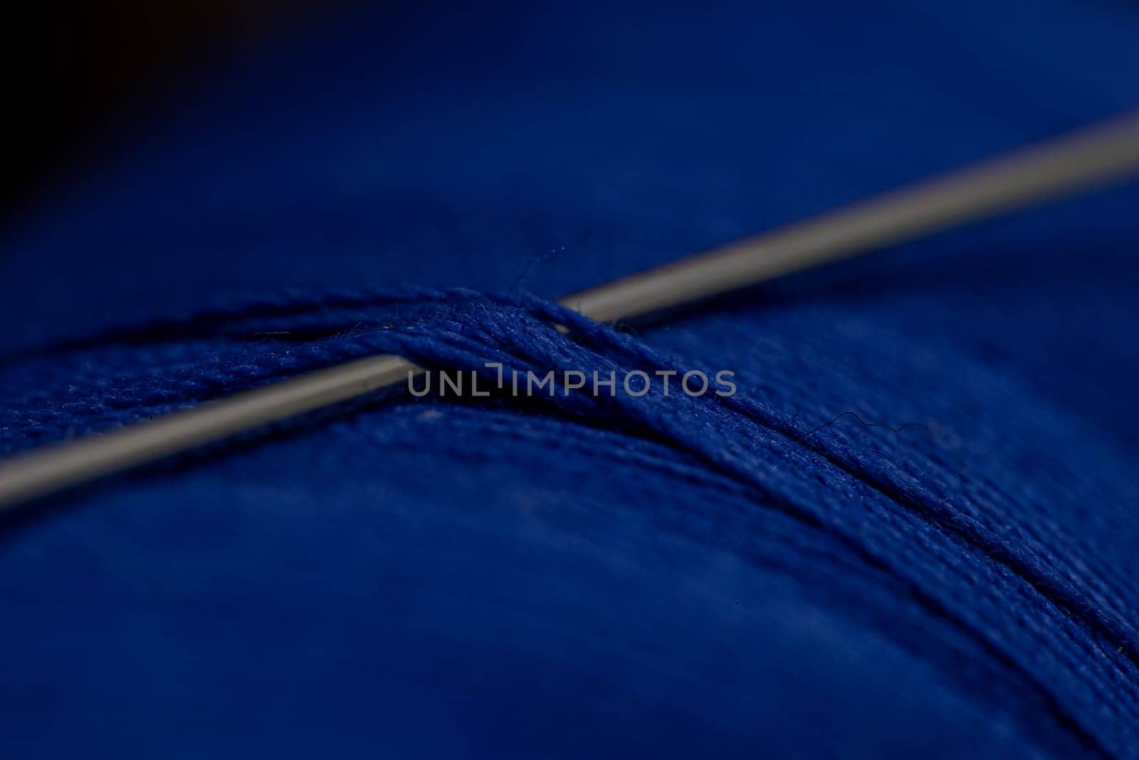 A detailed close-up shot of a needle in a blue thre