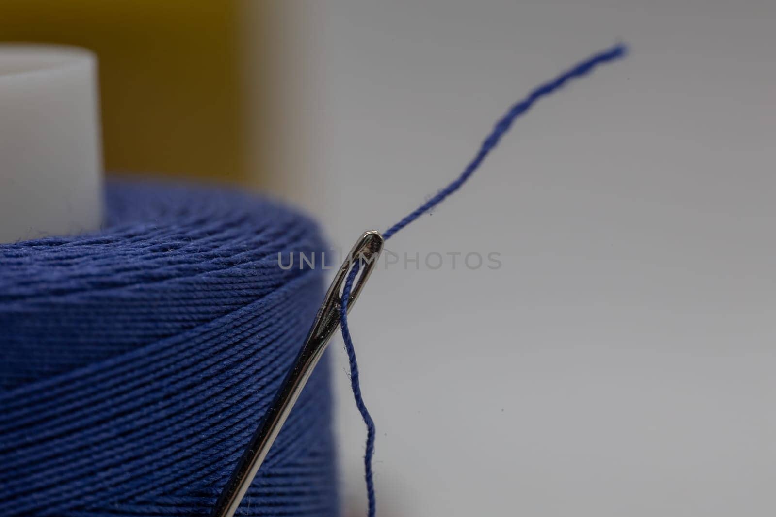 Closeup of a small needle in a blue thread on the blurry background by exndiver