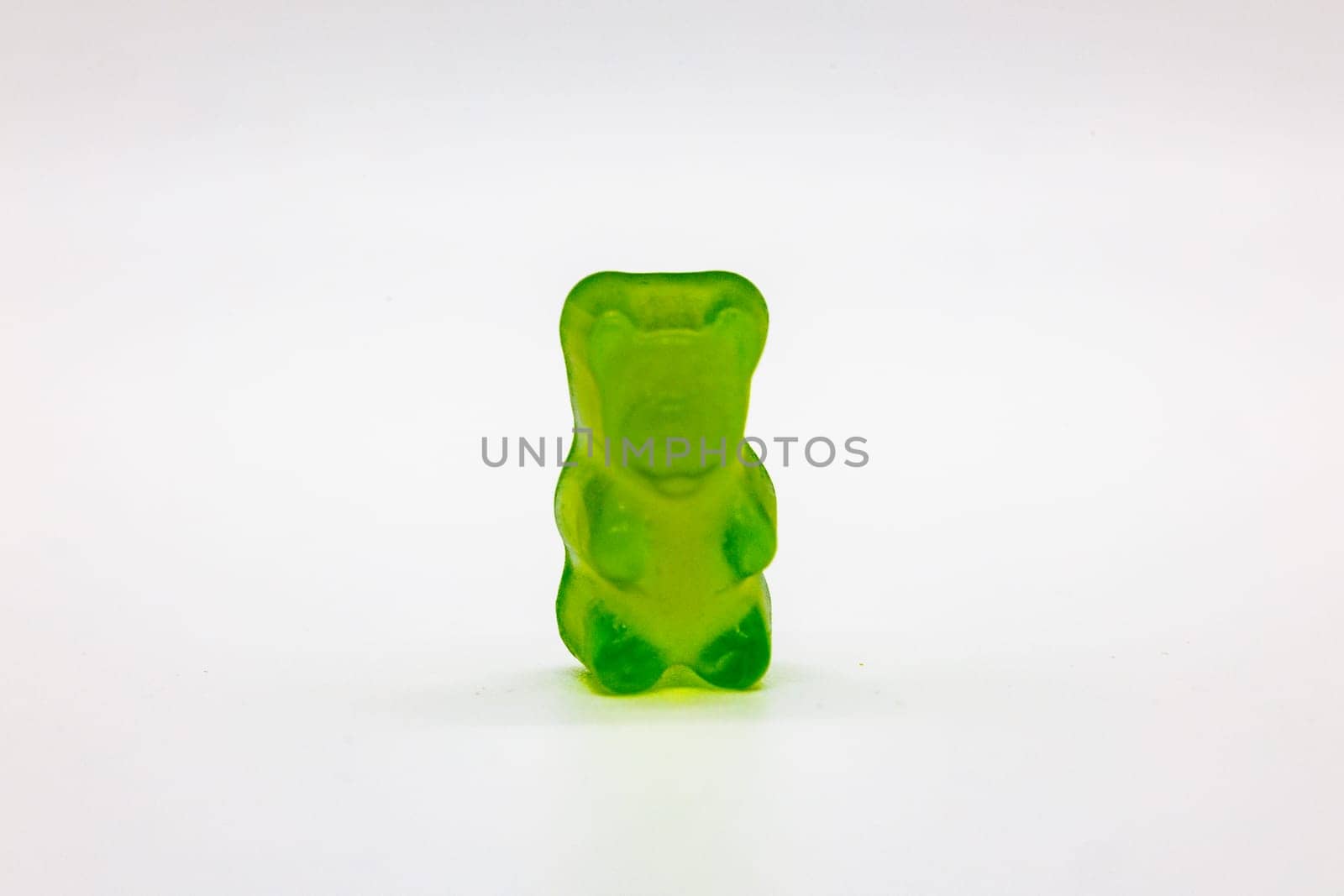 Isolated green gummy bear, sweet snack concept image.