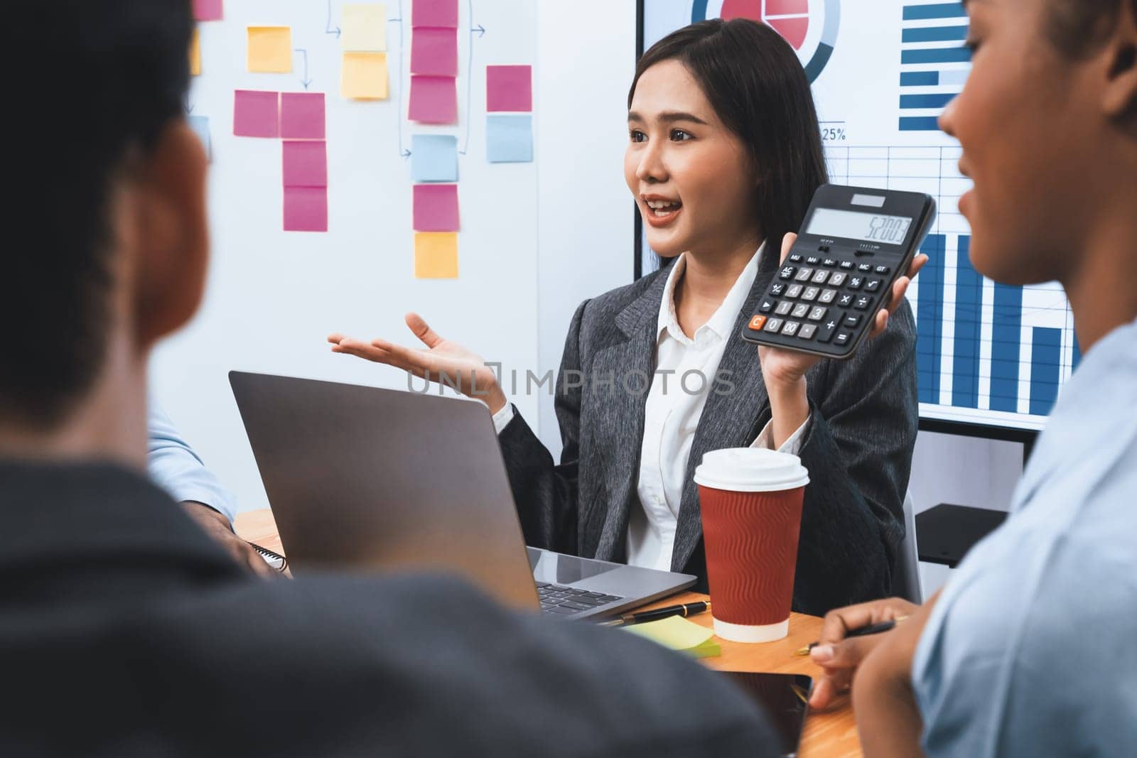 Multiracial analyst team use calculator and data science BI Fintech dashboard data to analyze financial report on office meeting table. Diverse business people for analytic teamwork. Concord