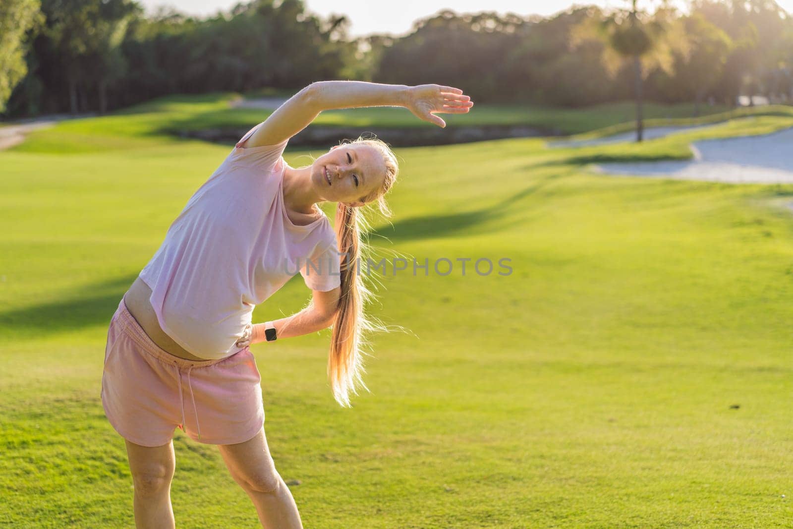 Energetic pregnant woman takes her workout outdoors, using an exercise mat for a refreshing and health-conscious outdoor exercise session.