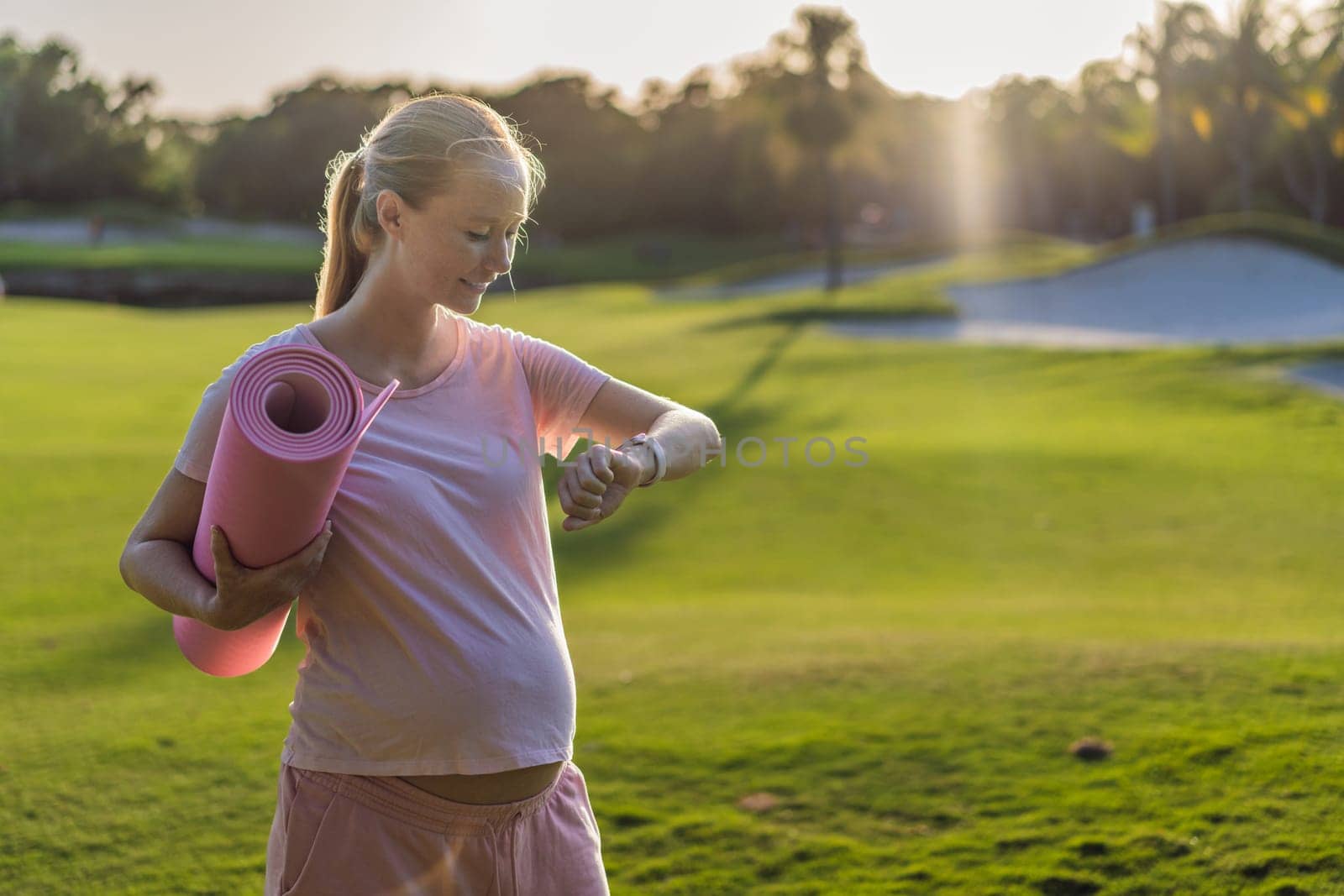 Energetic pregnant woman takes her workout outdoors, using an exercise mat for a refreshing and health-conscious outdoor exercise session by galitskaya