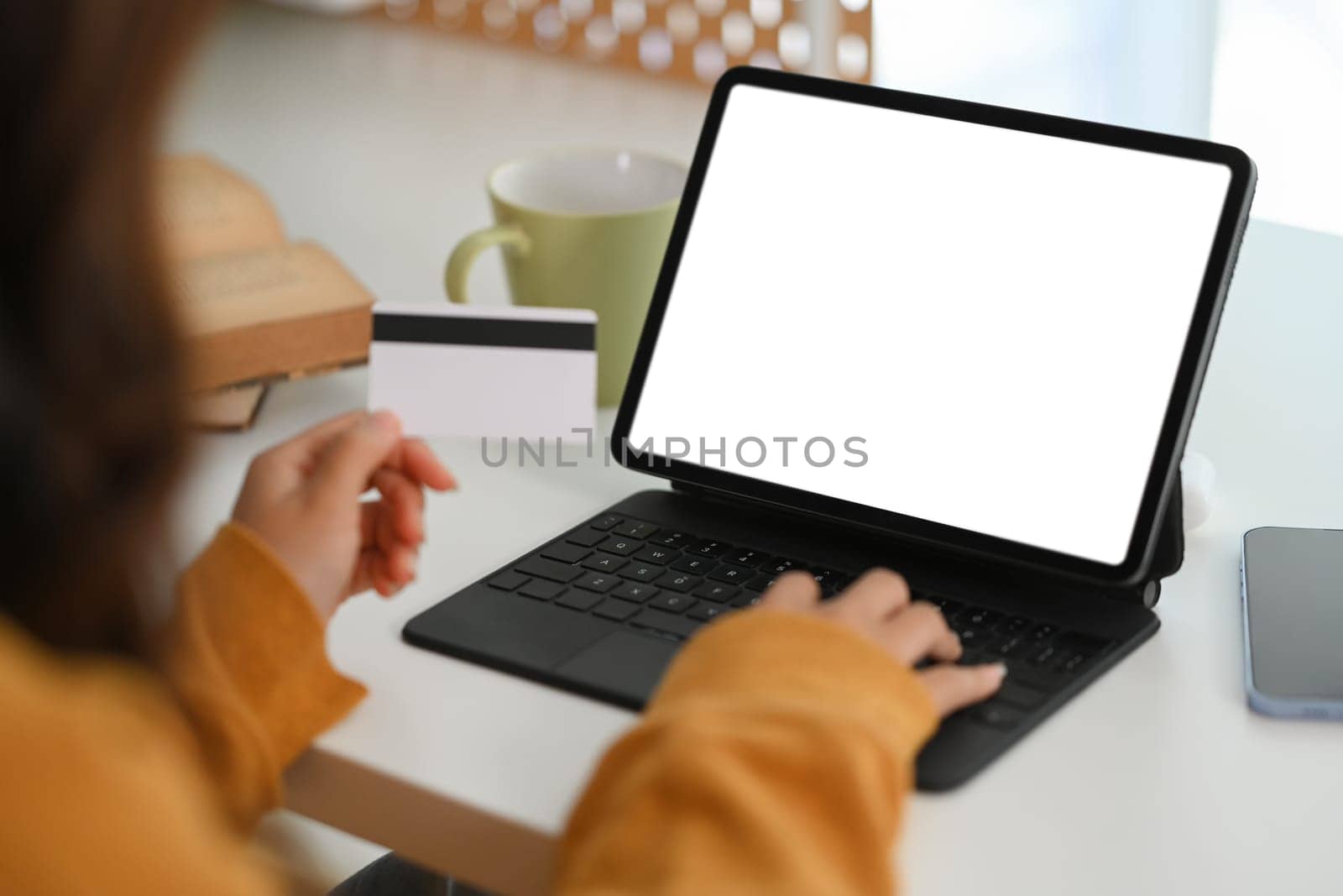 Closeup young woman holding credit card and using digital tablet making purchase on webstores.