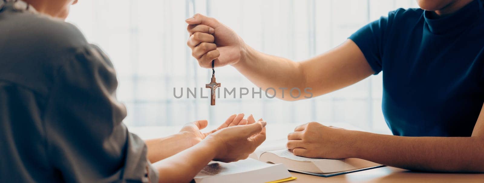 Close-up women prayer deliver holy bible book and holy cross to young believer. Spreading religion symbol. Concept of hope, religion, christianity and god blessing. Warm background. Burgeoning.