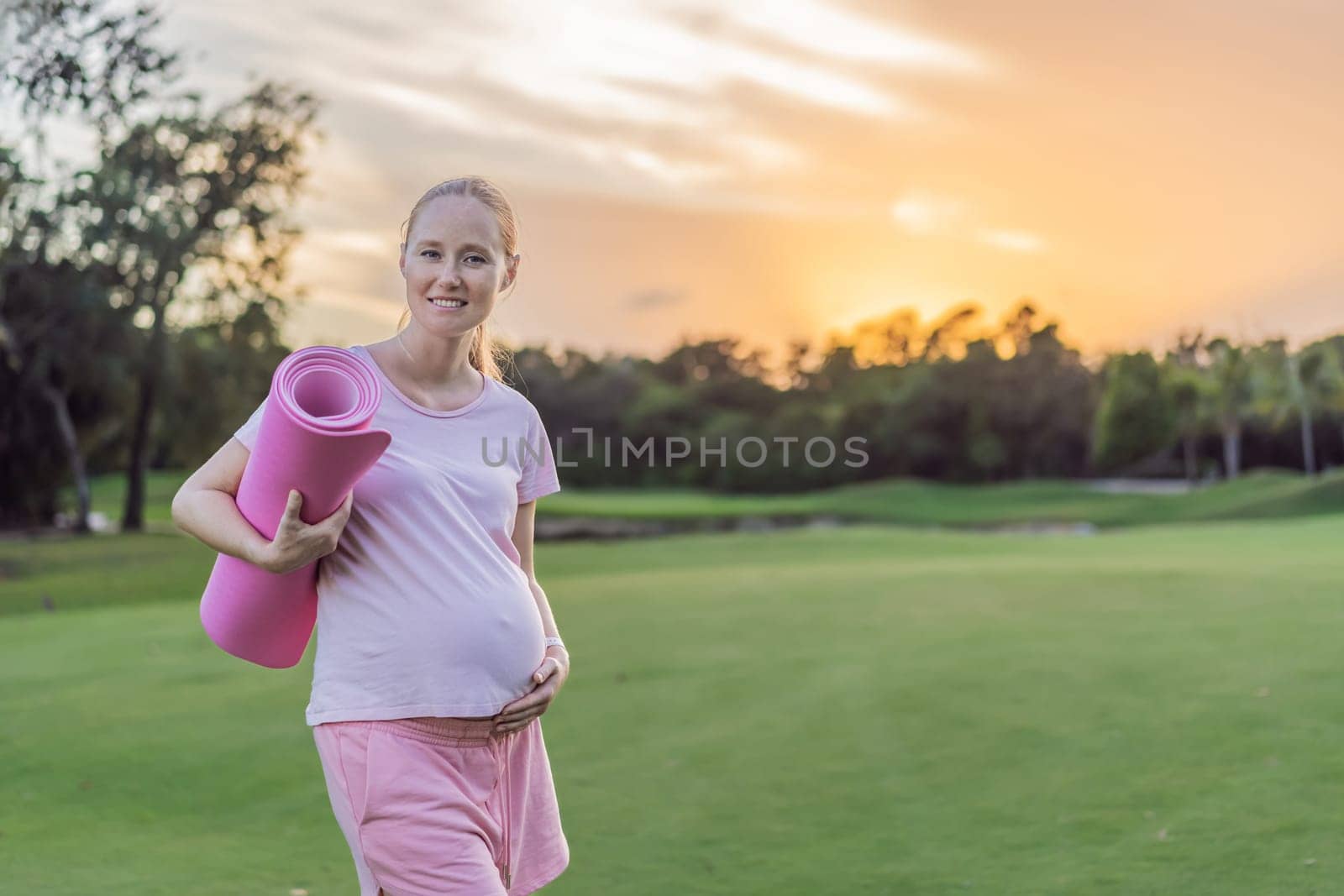 Energetic pregnant woman takes her workout outdoors, using an exercise mat for a refreshing and health-conscious outdoor exercise session.