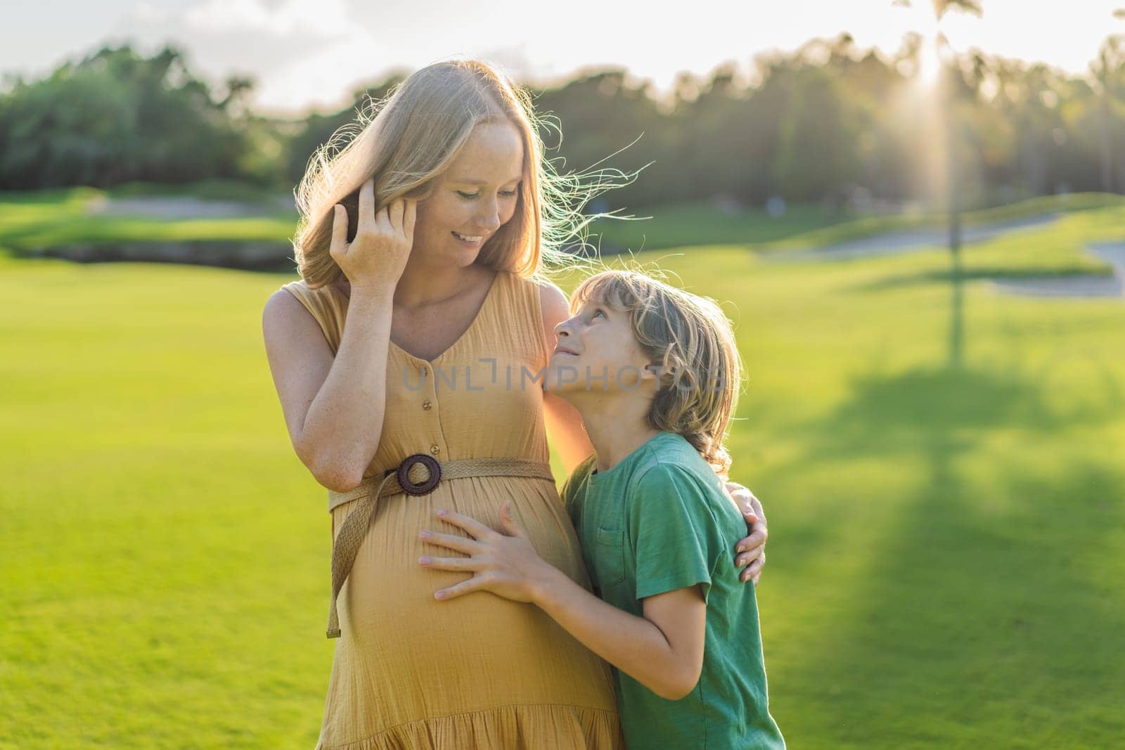 Heartwarming outdoor bonding as a pregnant mom and her son enjoy quality time together, savoring the beauty of nature and creating cherished moments by galitskaya