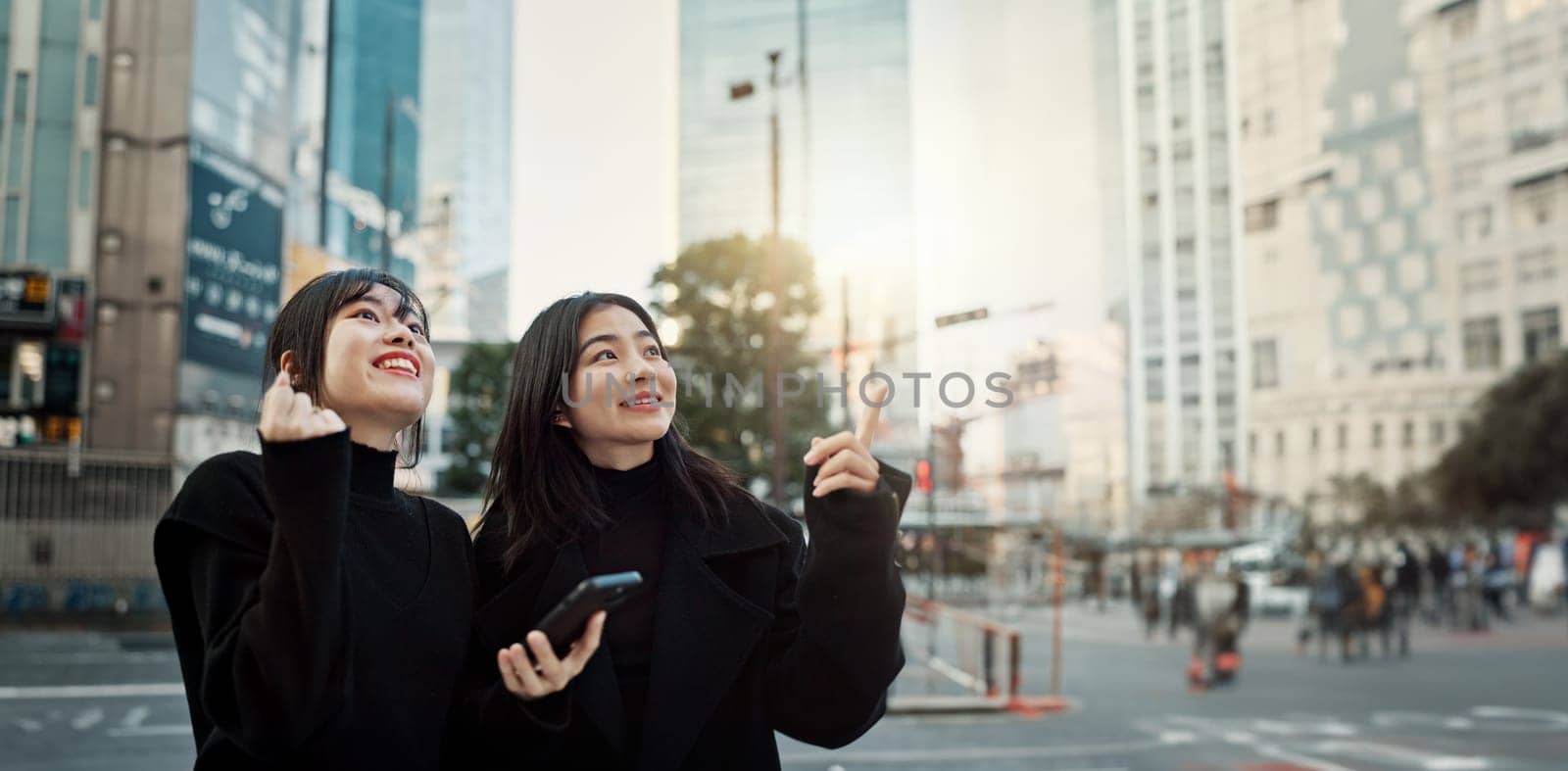 Phone, friends and women pointing in city for travel, social media and connection together in Japan. Smartphone, girls and happy people in urban street outdoor to commute with digital app in Tokyo.