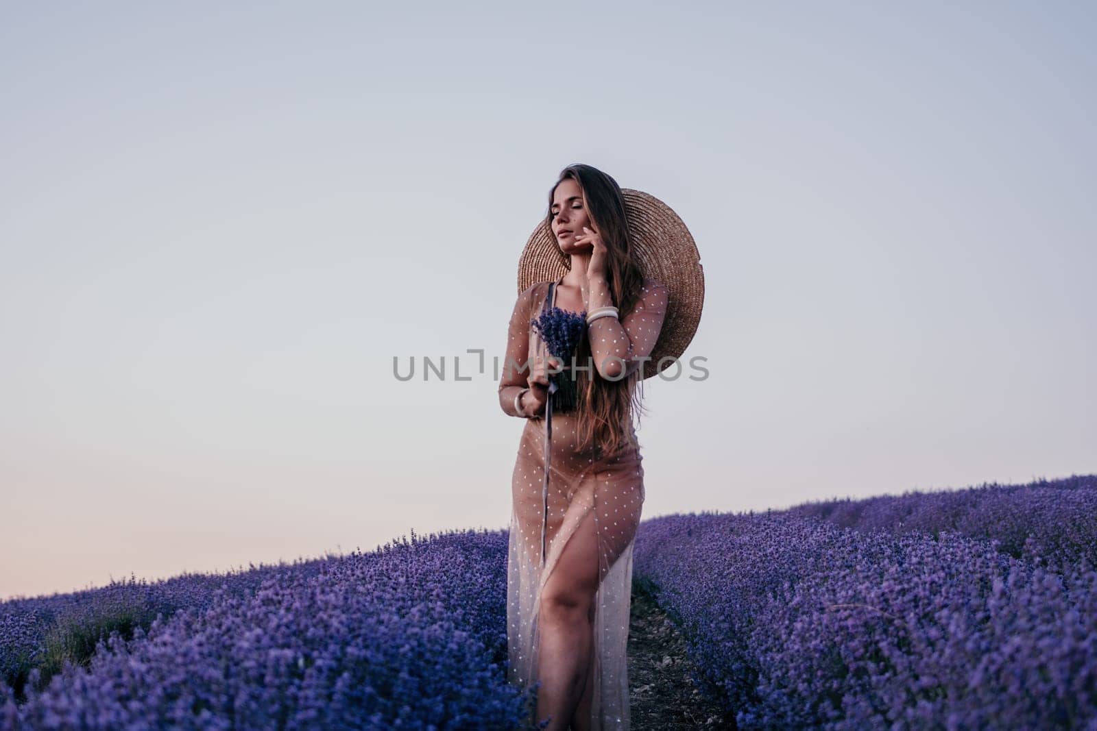 Woman lavender field. Happy carefree woman in beige dress and hat with large brim smelling a blooming lavender on sunset. Perfect for inspirational and warm concepts in travel and wanderlust. Close up by panophotograph