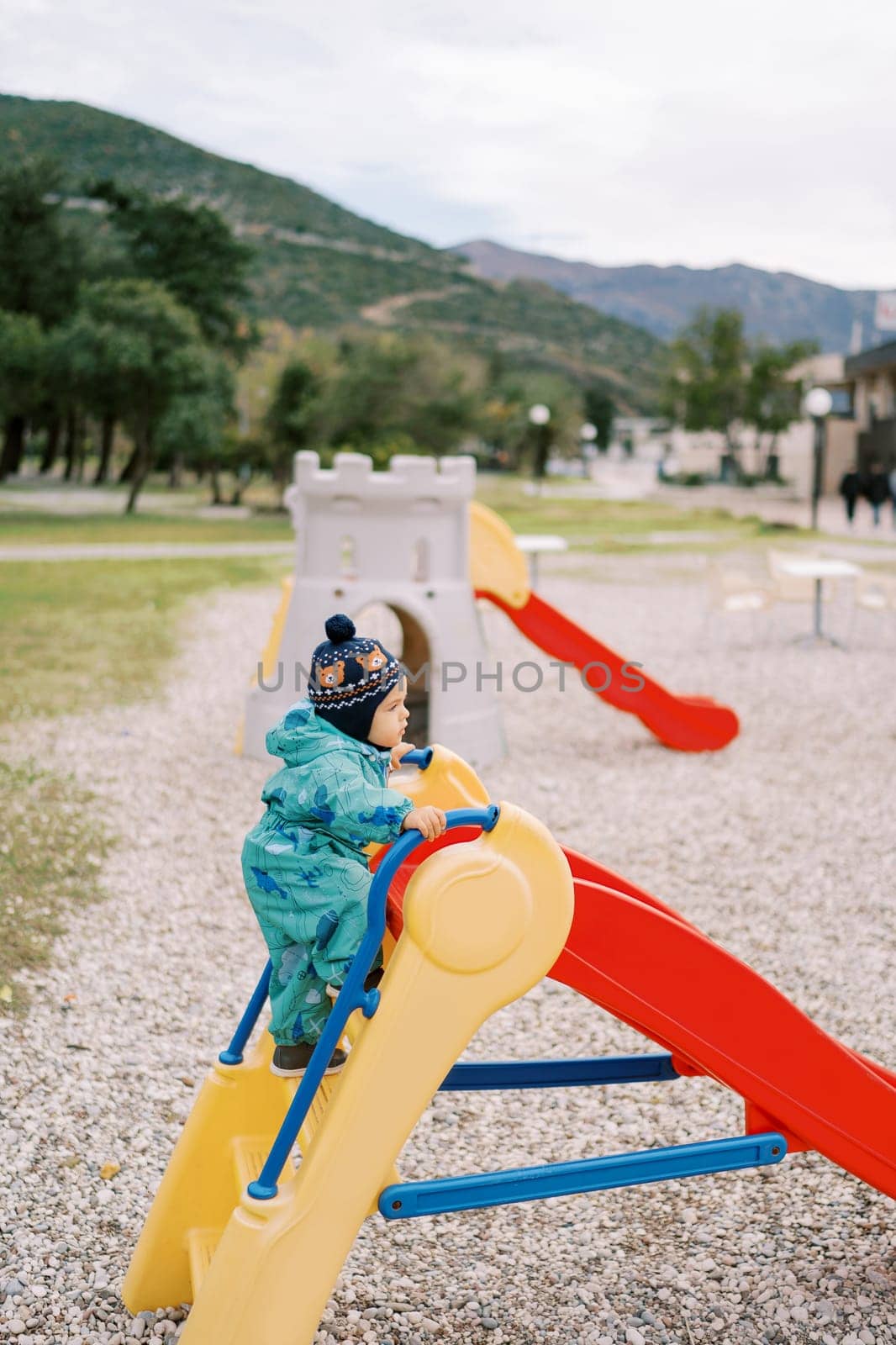Little girl climbs the stairs to the colorful slide in the playground. Side view. High quality photo