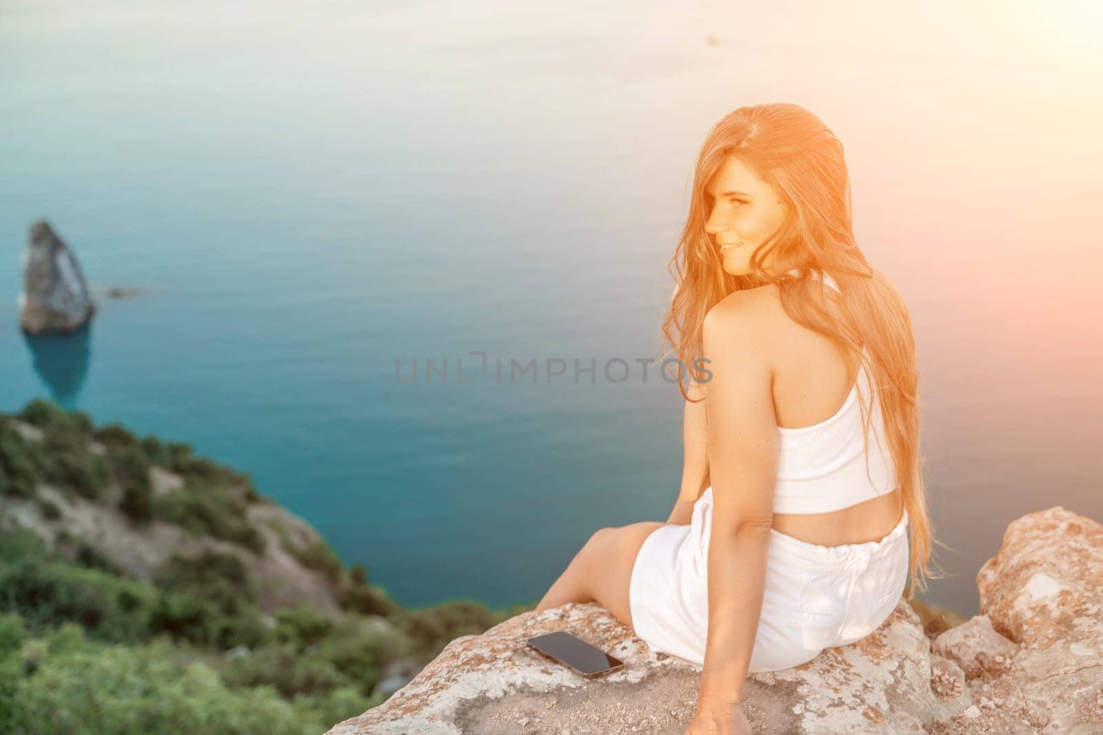 woman sea. portrait in white shorts and T-shirt with long hair, standing against the sea, showcasing her joyful and contented mood