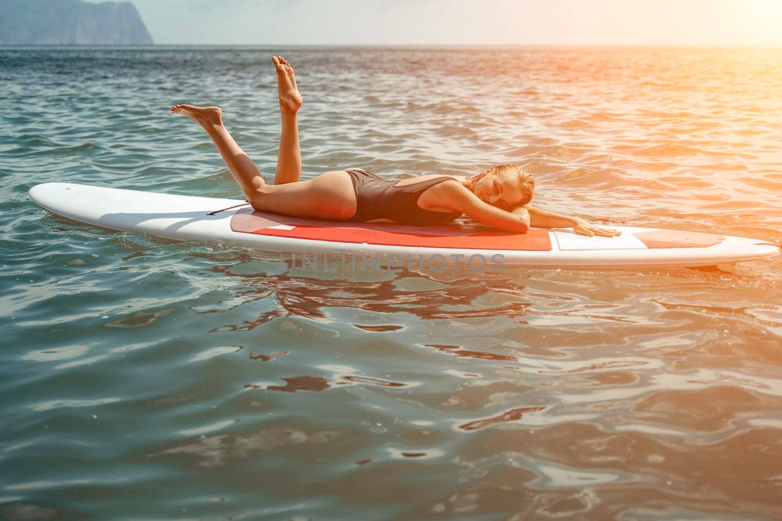 Woman sup sea. Sports girl on a surfboard in the sea on a sunny summer day. In a black bathing suit, he sits on a sapa in the sea. Rest on the sea. by Matiunina