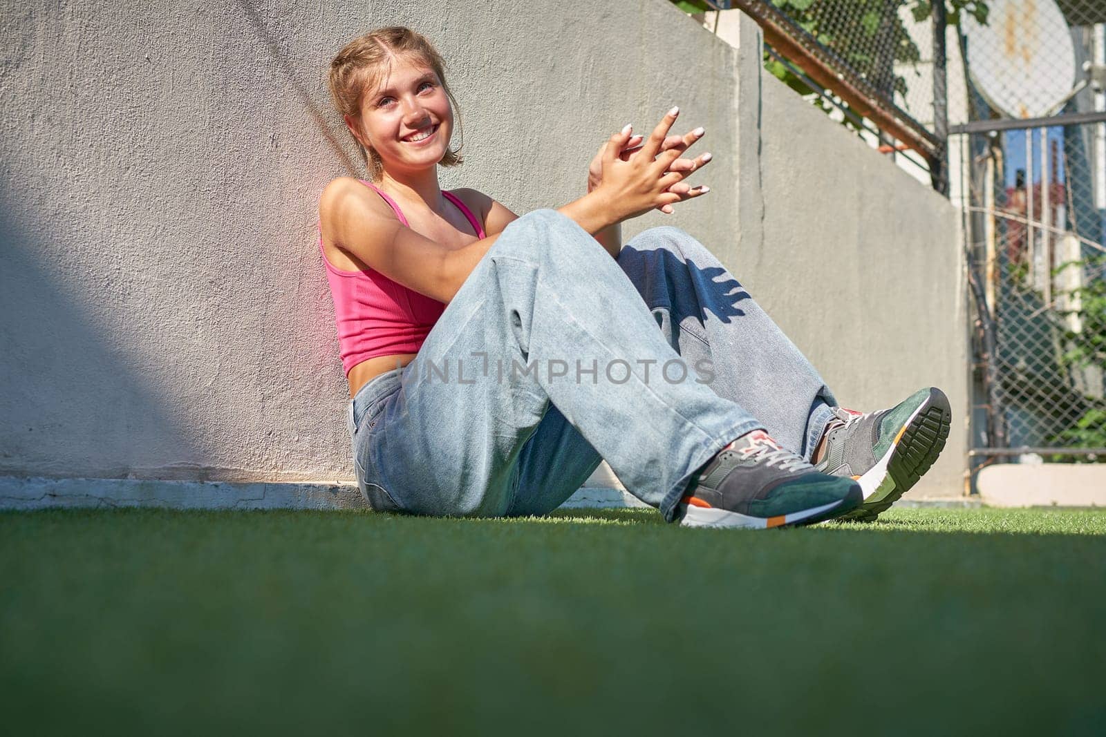 Radiant bliss girl sitting on the sports ground looking at the camera.